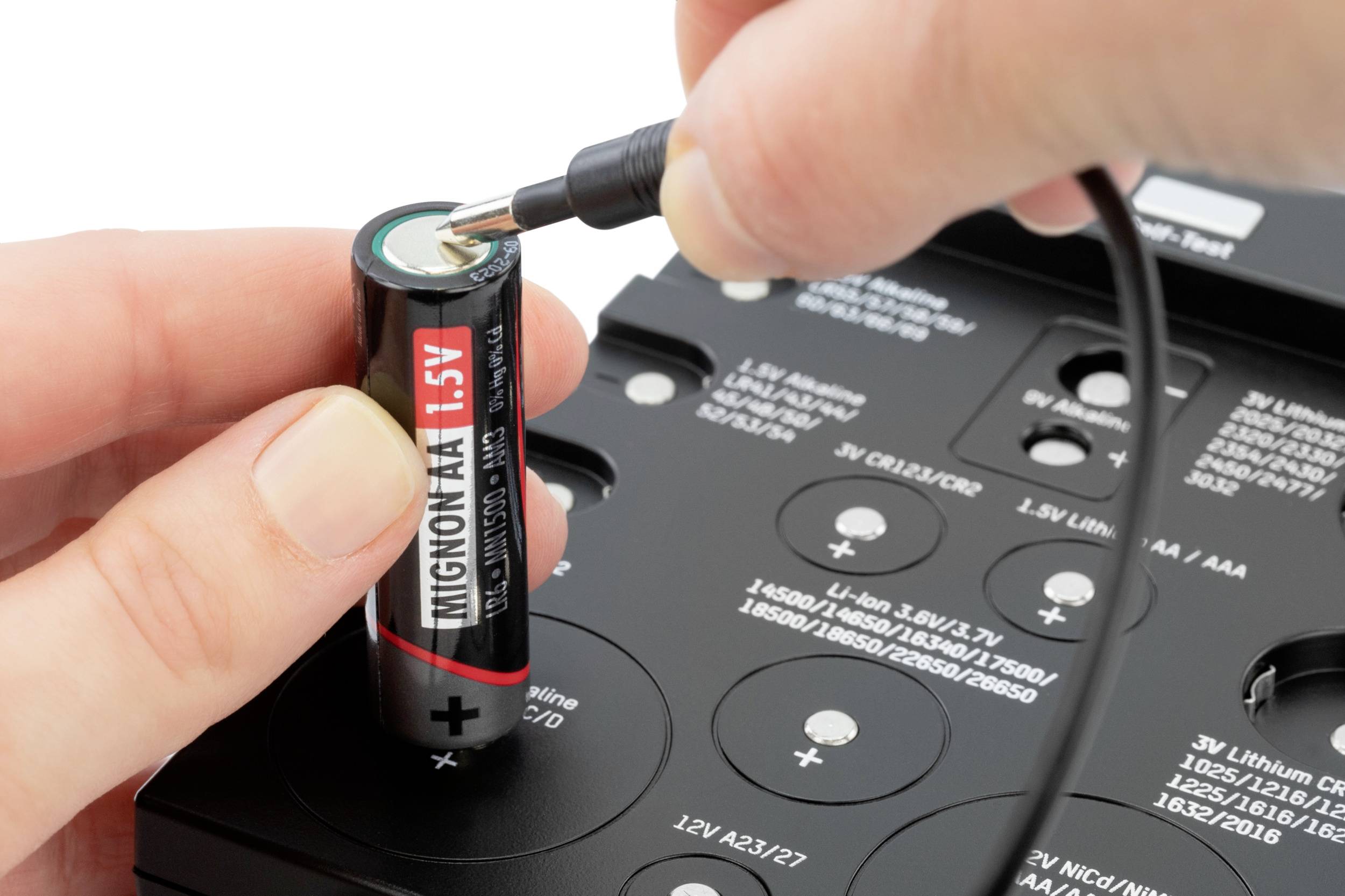 Een AA-batterij wordt opgeladen met een oplader. Een hand houdt de batterij vast terwijl een kabel is aangesloten op de oplader.