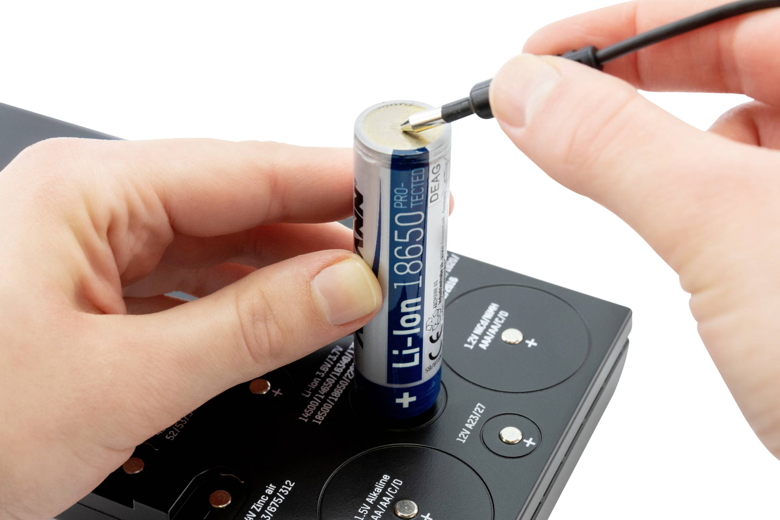 Een persoon test een 18650-type lithium-ion batterij met een apparaat, terwijl deze op een oplader is geplaatst.
