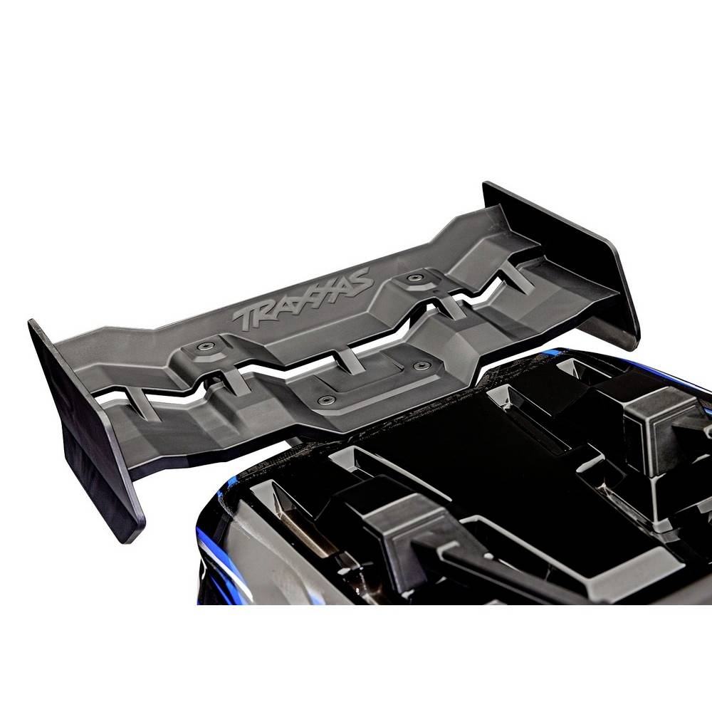 Zwarte RC-autospoiler met 'Traxxas'-logo, gemonteerd op een donkere modelauto.