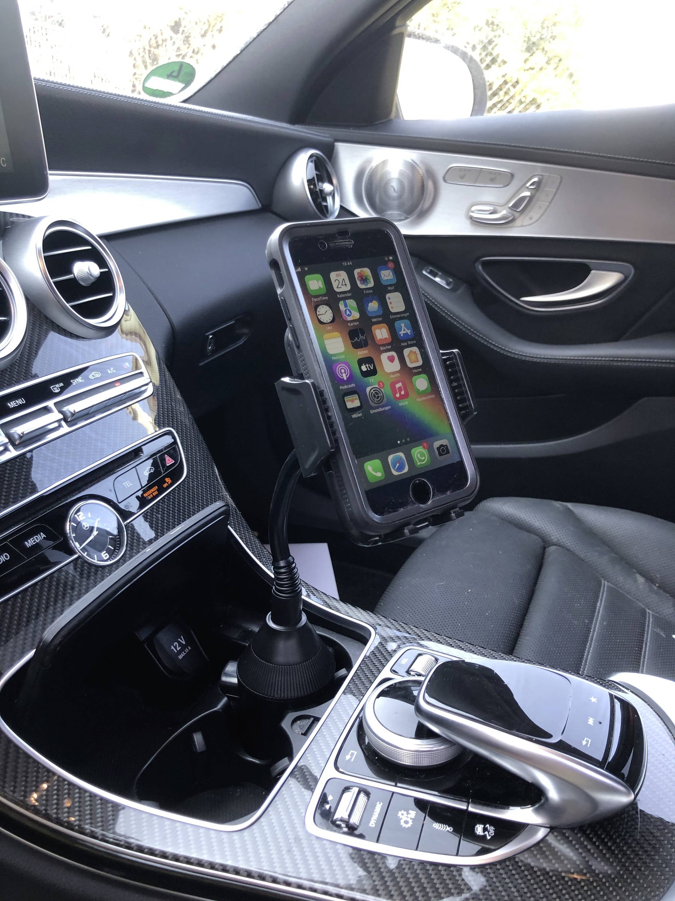 Smartphonehouder in de auto, bevestigd aan de middenconsole, houdt een smartphone met een kleurrijk app-scherm vast.
