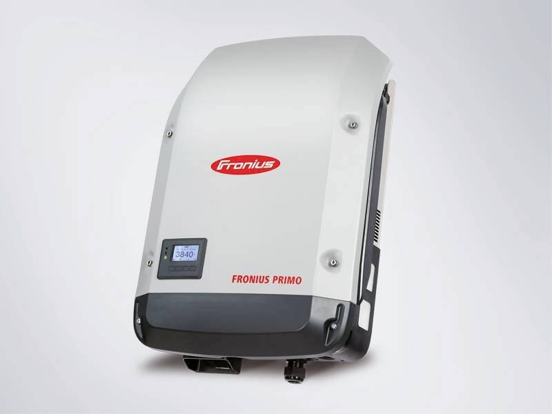 Een witte Fronius Primo omvormer met display aan de voorkant dat het huidige vermogen weergeeft.