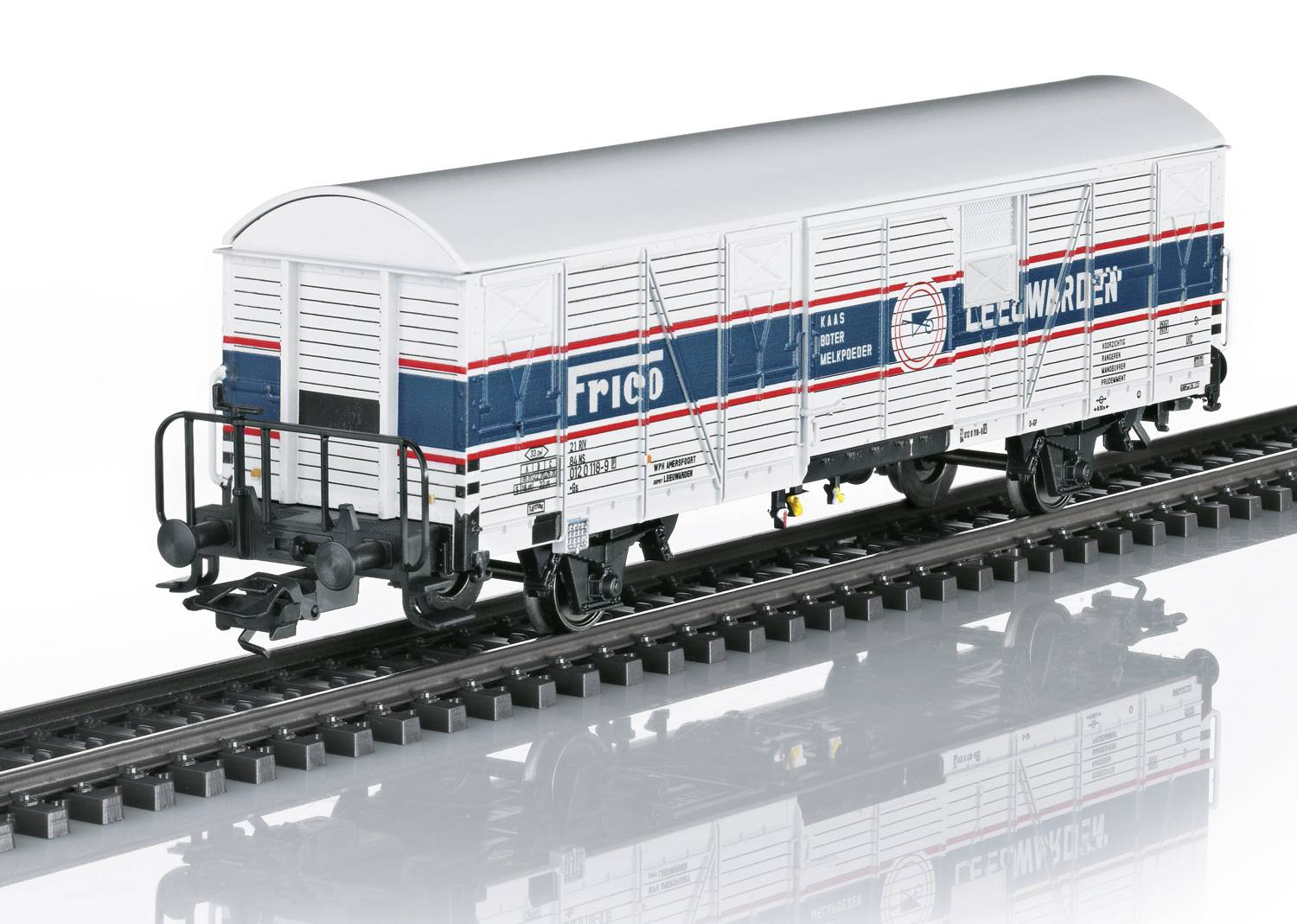 Een modeltrein goederenwagen met 'FRICO' en 'Leerdam Vaderdag' opschrift, geplaatst op een spoor. Wit behuizing met blauwe en rode strepen.