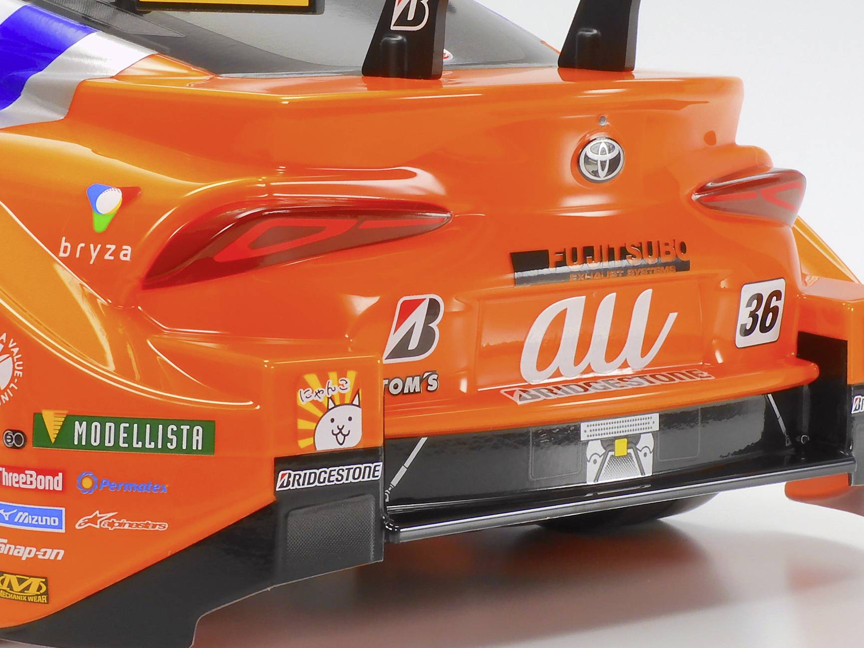 Speelgoedauto in het oranje, nabootsing van een racewagen. De achterkant toont merkenlogo's en startnummer 36.