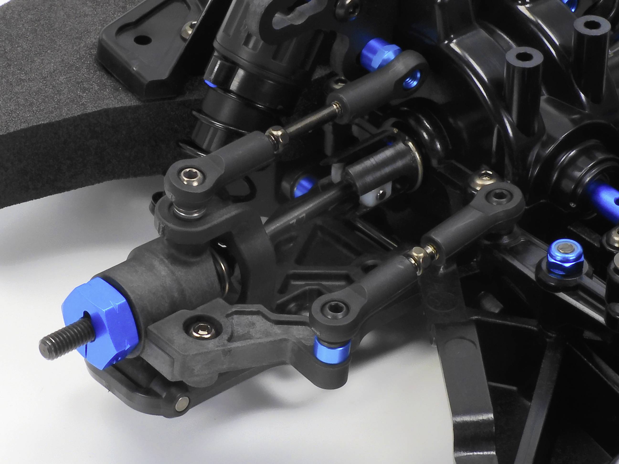 Close-up van een technisch RC-autoonderdeel met gewrichtsverbindingen en schroeven, onthult details van de ophanging en mechaniek.