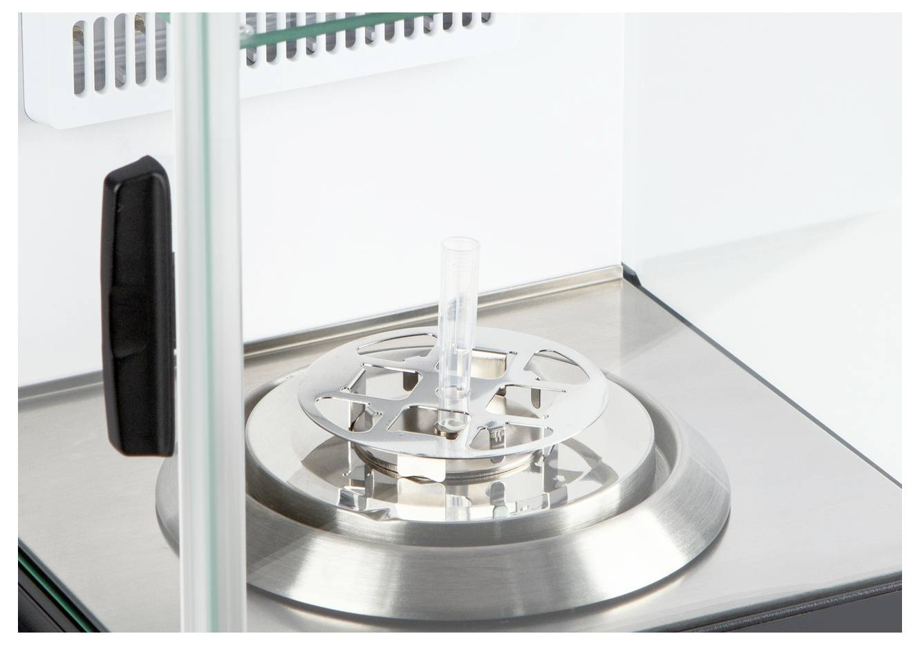 Een laboratoriumvoorziening in een steriele kamer, die een ronde metalen platform met een centraal glazen buis toont.