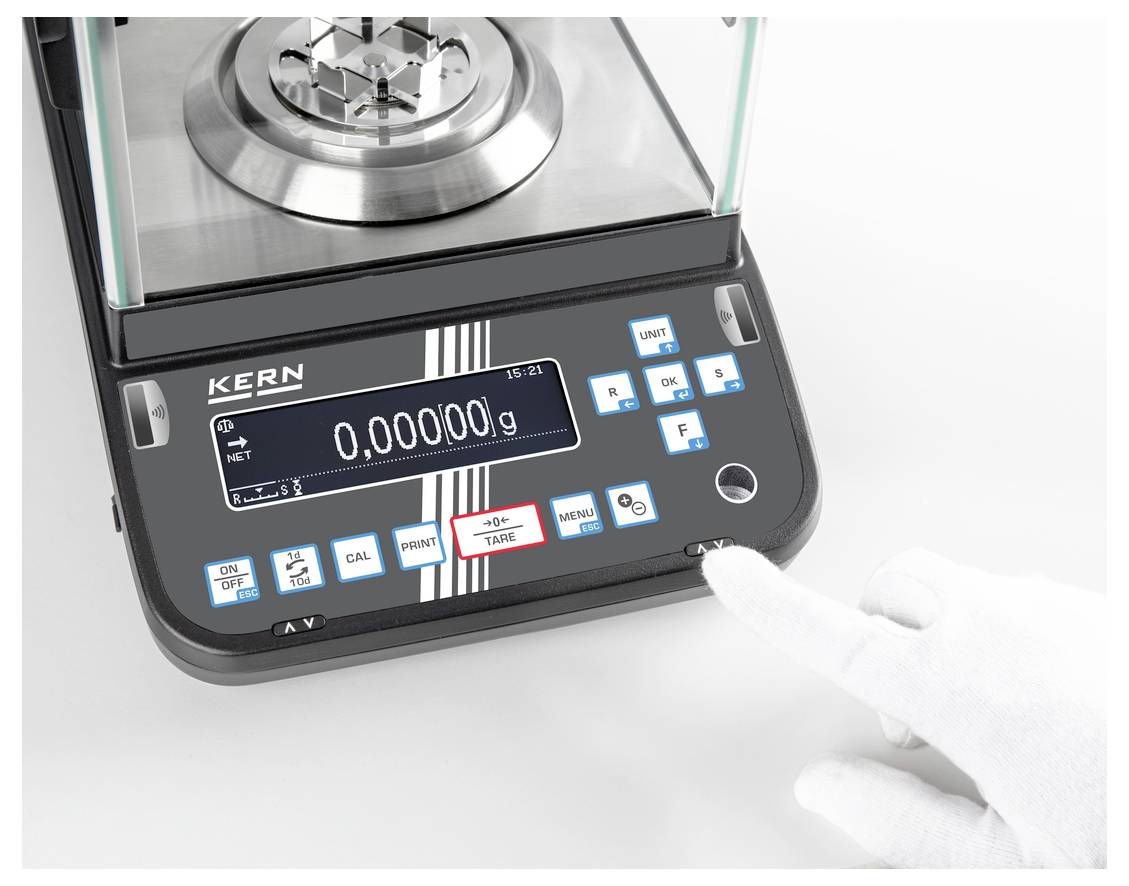 Een elektronische weegschaal toont het gewicht '0,00000 g'. Een hand in een witte handschoen raakt de toets 'TARE' naast het display aan.