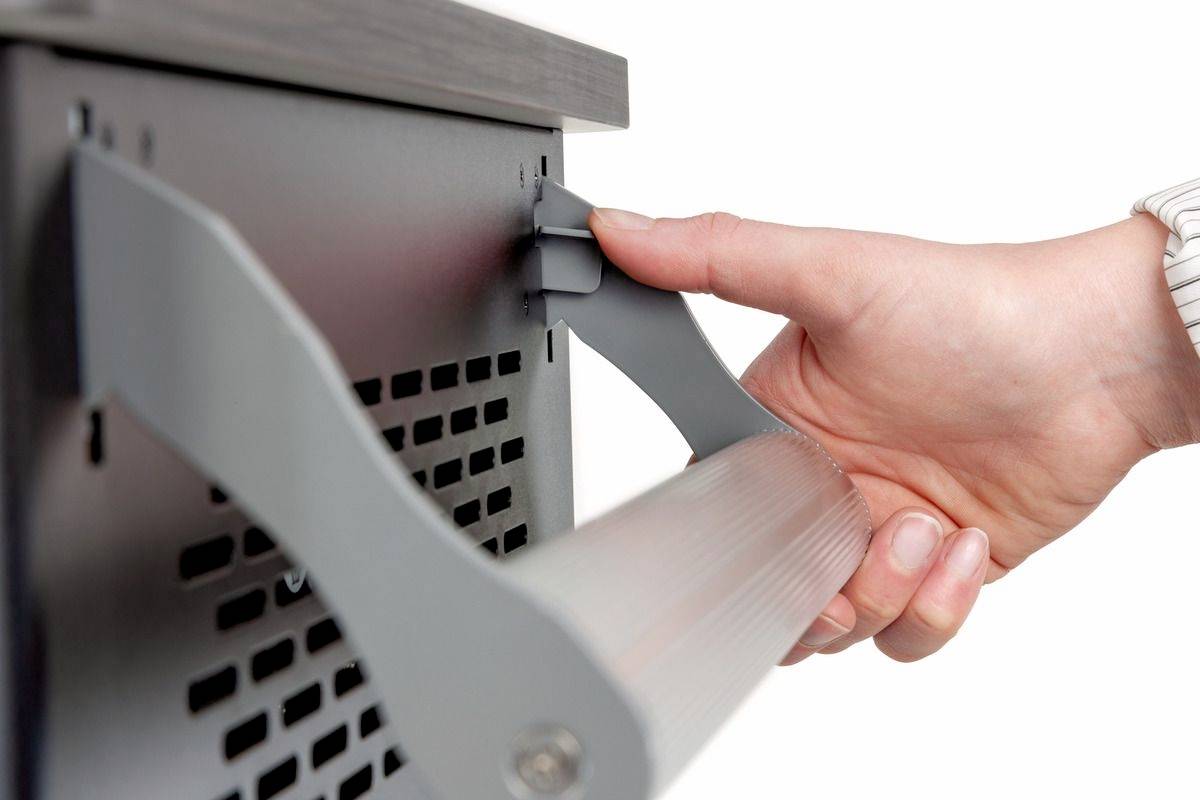 Een hand trekt aan een grijze hendel van een elektronisch apparaat. Het lijkt erop dat een afdekking of klep wordt geopend.