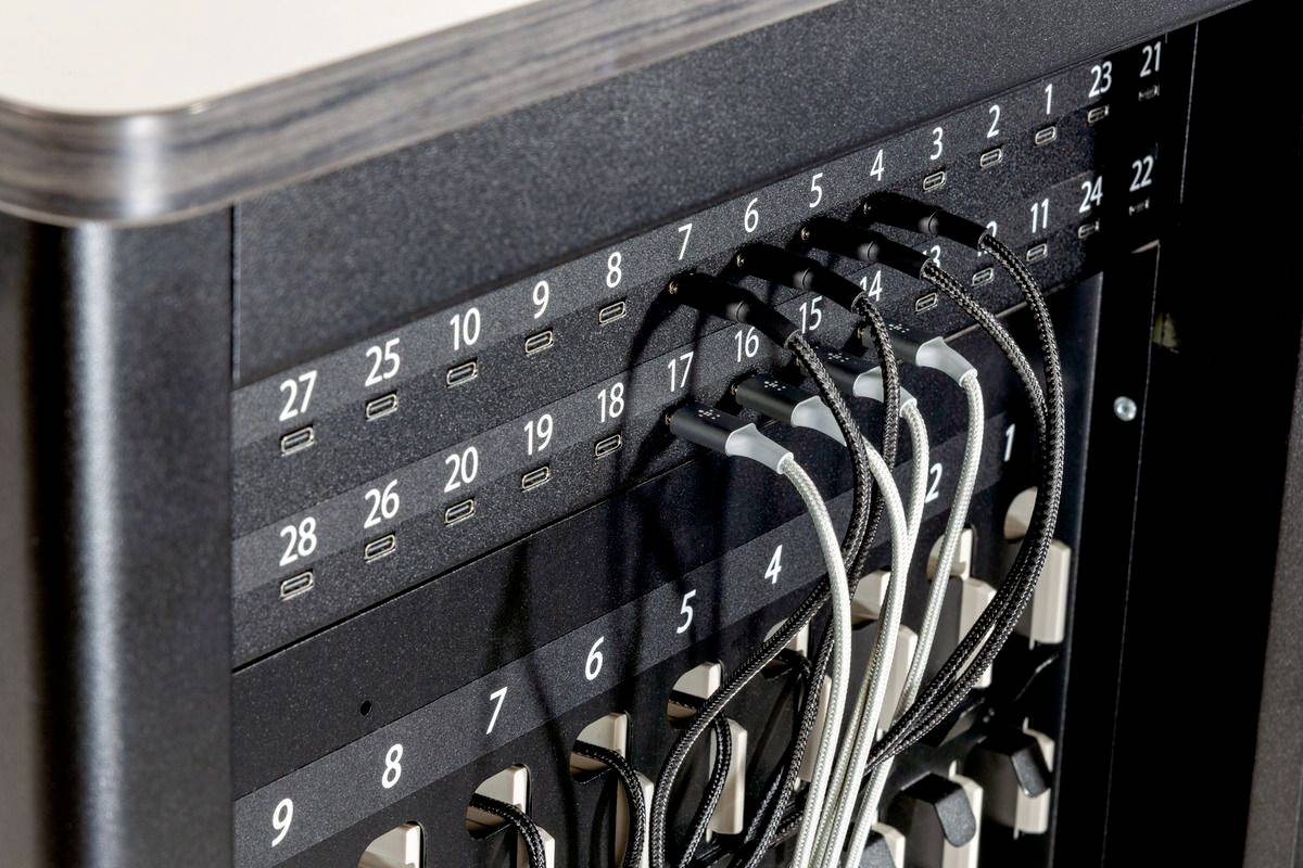 Een zwart apparaat met meerdere aangesloten USB-kabels in genummerde poorten van 16 tot 28, gebruikt voor gegevensverbindingen.