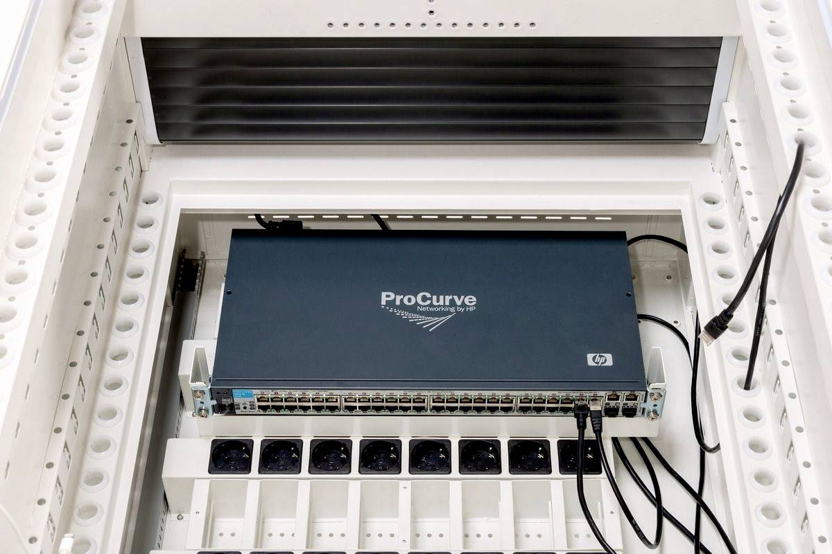 Een HP 'ProCurve' netwerk-switch in een serverrek, omringd door kabels. De voorkant toont meerdere Ethernet-poorten.