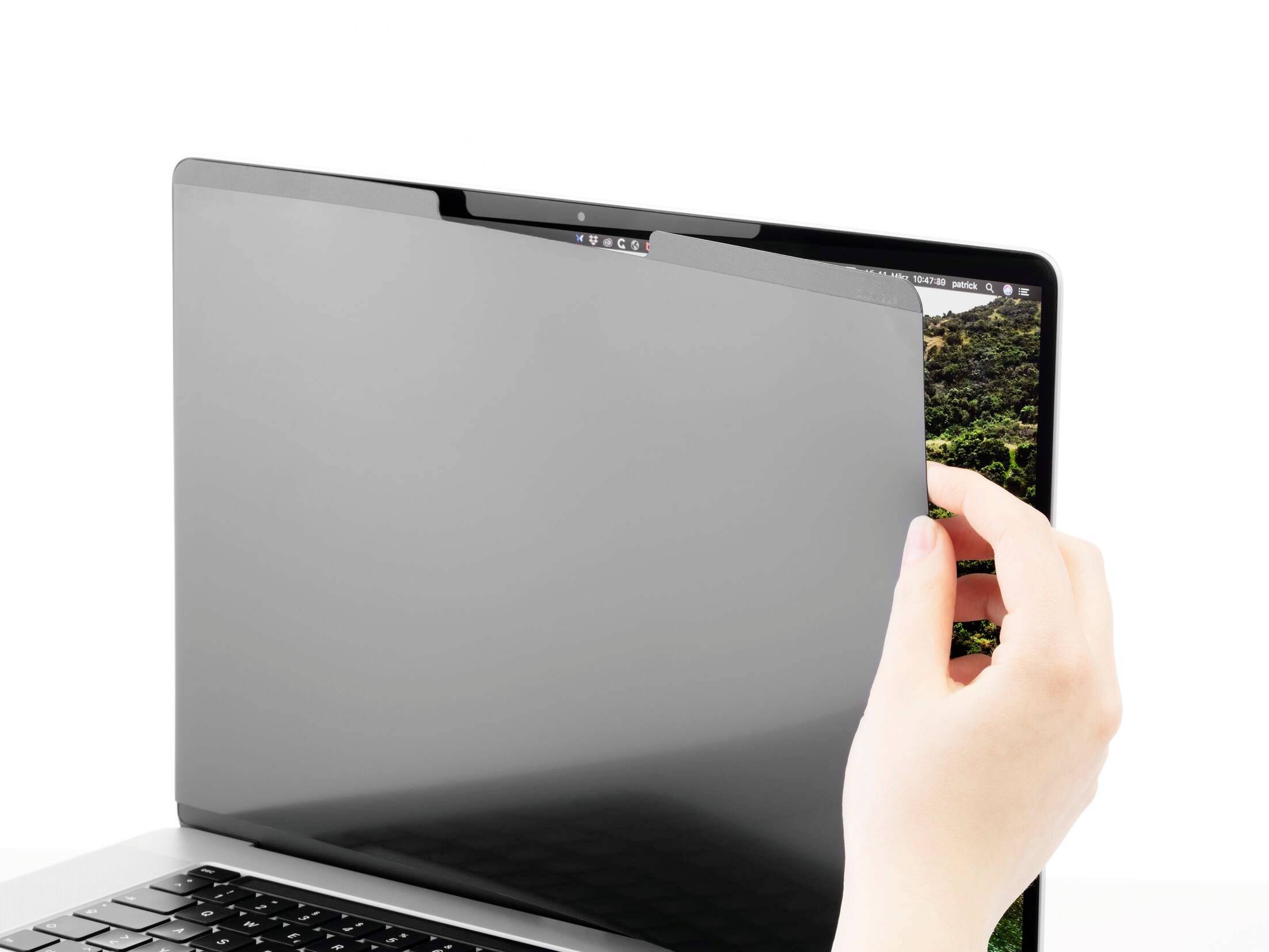 Een hand houdt een privacyfilter vast die op een laptopscherm wordt geplaatst om de inhoud te beschermen tegen ongewenste inkijk.
