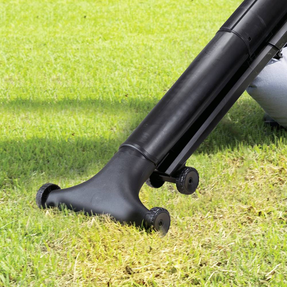 Een zwart grasmaaiwerktuig dat gras aan het beluchten is op een zonnige dag.