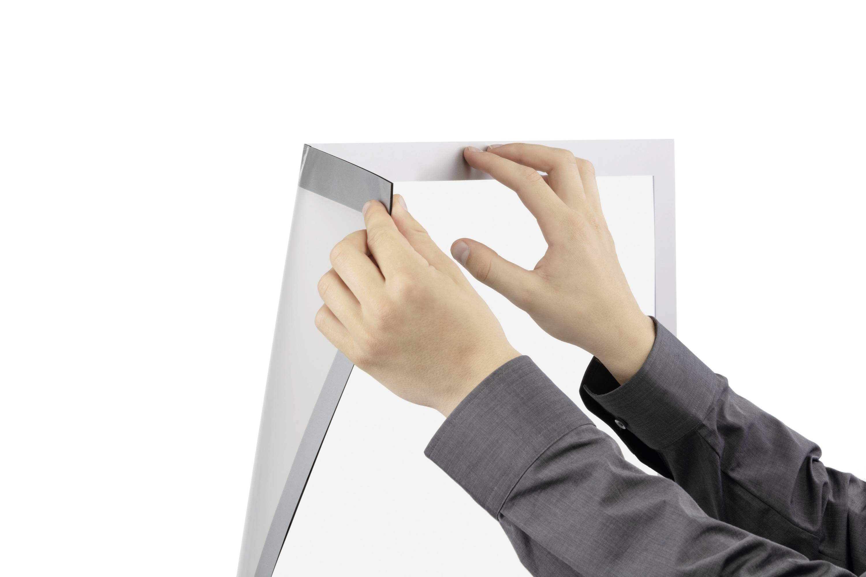 Een persoon houdt een wit vel papier met beide handen vast boven een zilveren oppervlak. De handen houden het papier vast aan de rand.