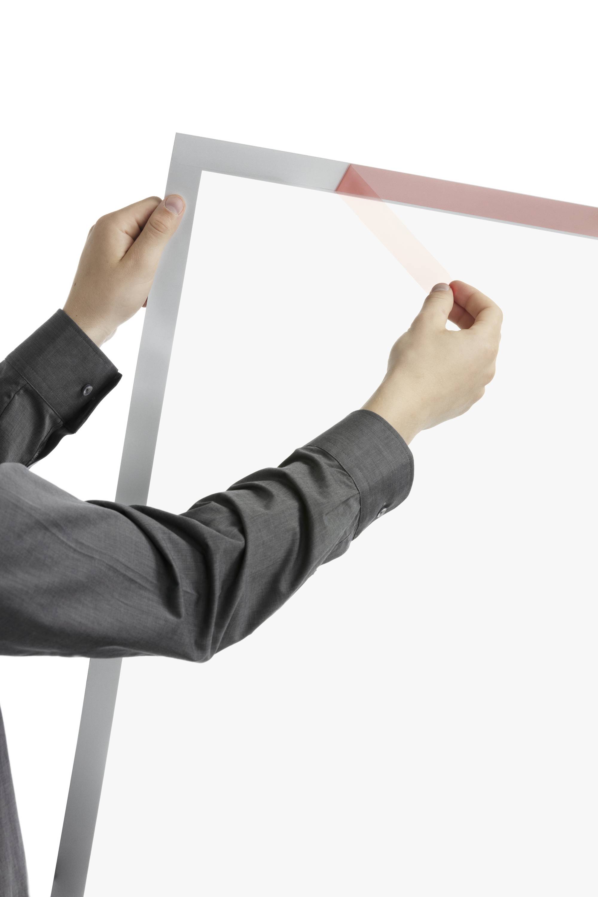 Een persoon in een grijs shirt houdt een grote lijst van transparant materiaal vast. De lijst heeft een lichte omlijsting.