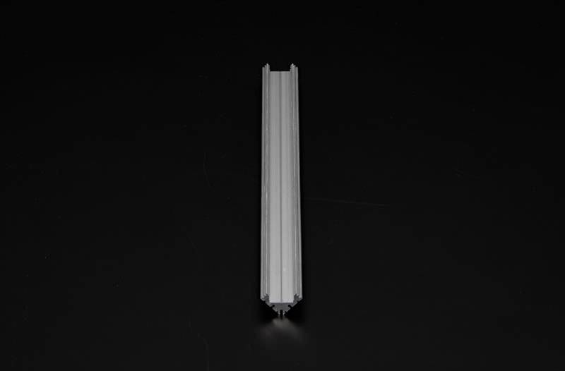 Een grijze, metaalachtige, langwerpige rail ligt op een zwarte achtergrond. Hij is symmetrisch met twee parallel lopende randen.