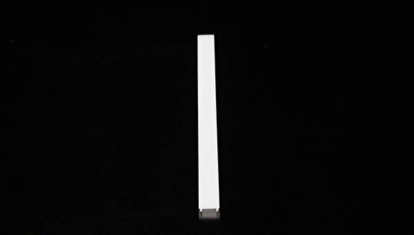 Een lange, witte, rechthoekige staaf staat verticaal op een zwarte achtergrond.