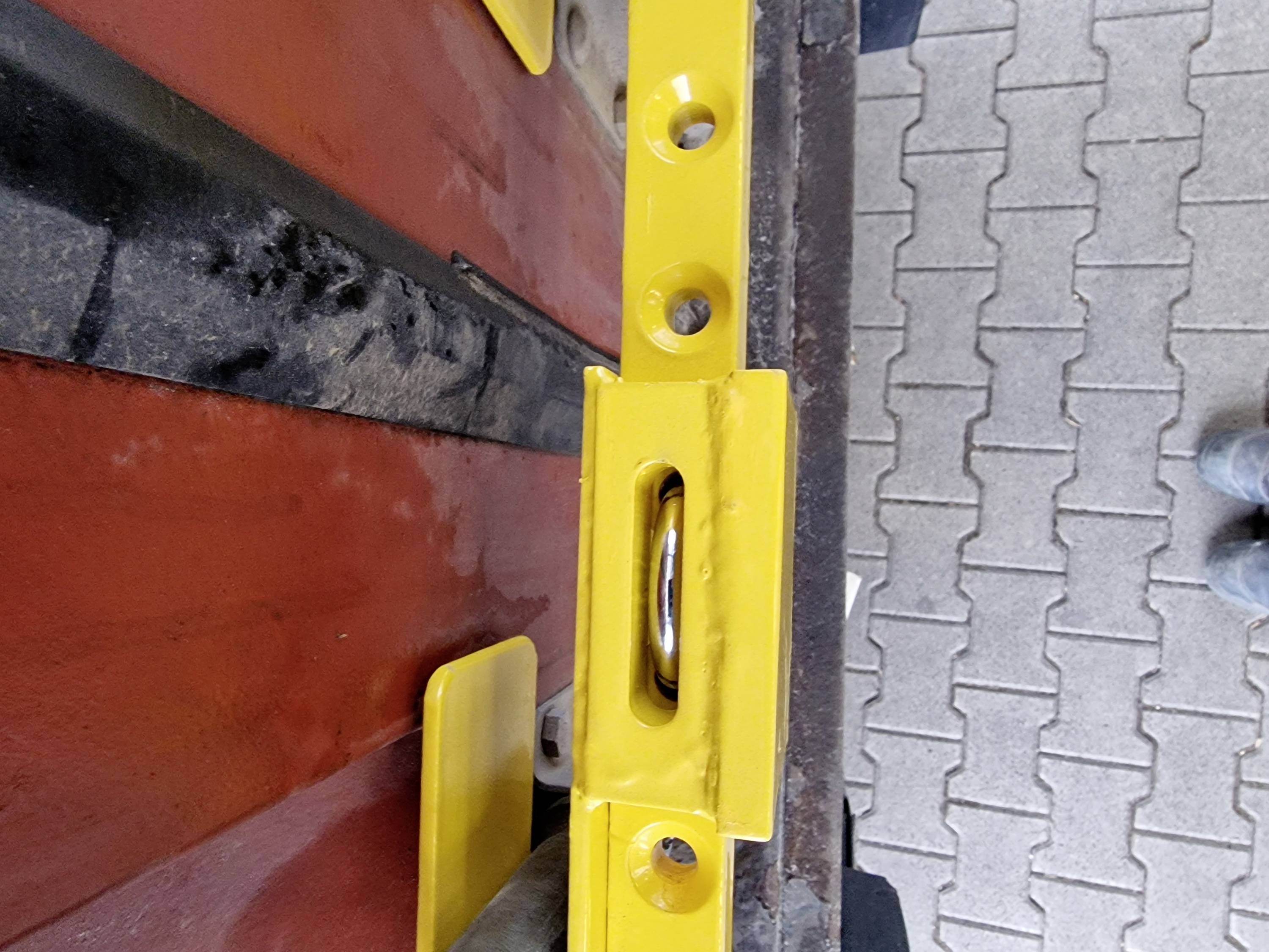 Gele waterpas op rood hout en betonvloer, geeft de waterpassing aan tijdens de bouw of montage.