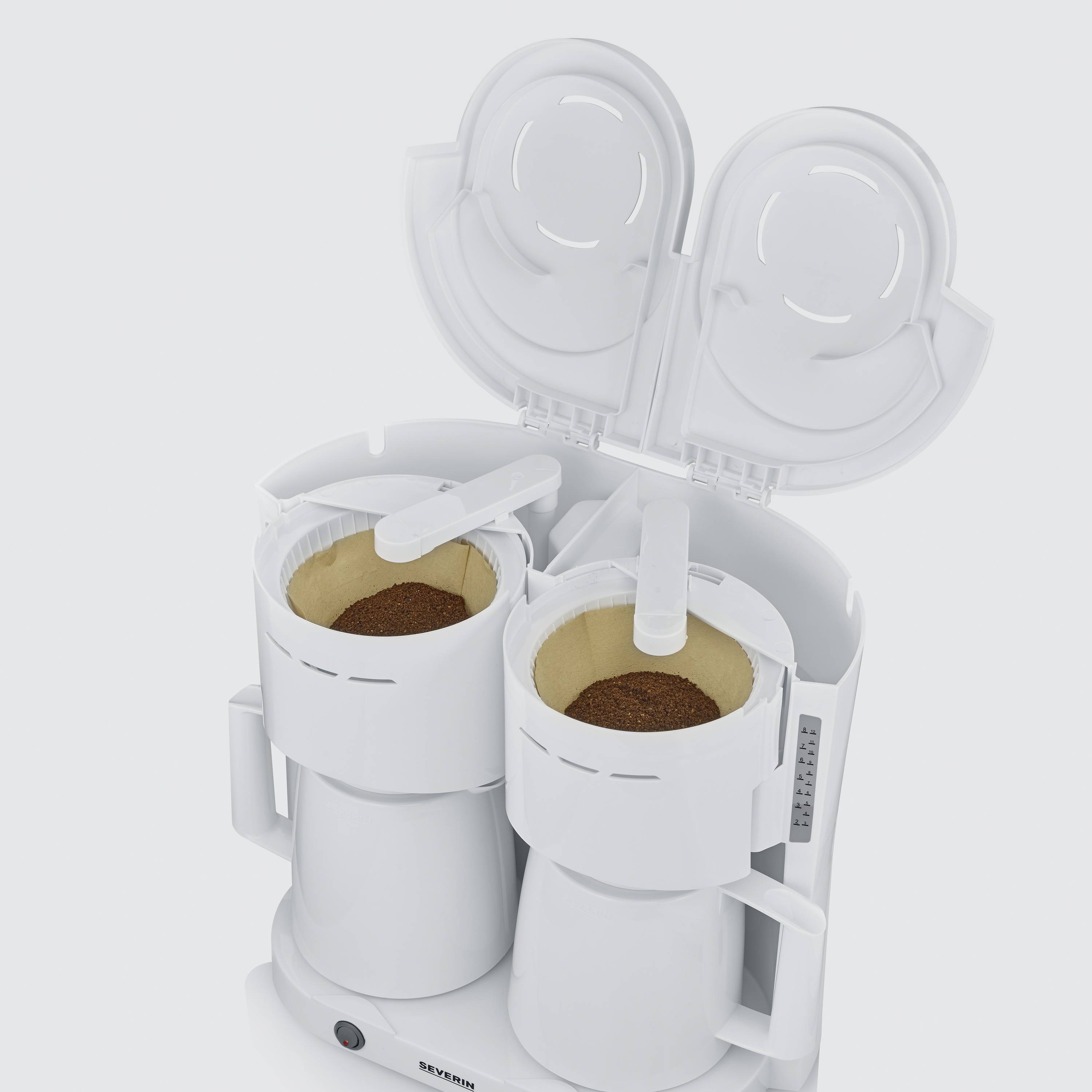 Twee witte koffiemachines met geopende deksels, gevuld met koffiepoeder, staan naast elkaar op een wit oppervlak.