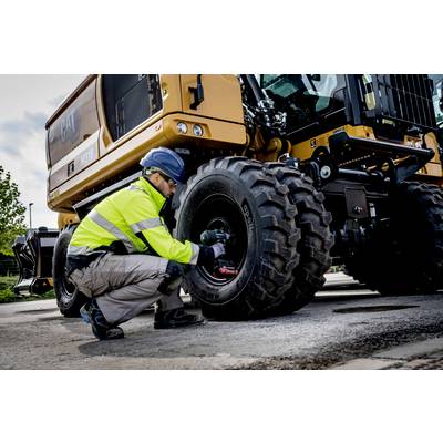 Een arbeider in veiligheidskledij controleert een zwaar bouwvoertuig. Hij draagt een veiligheidshelm en inspecteert de wielonderdelen.