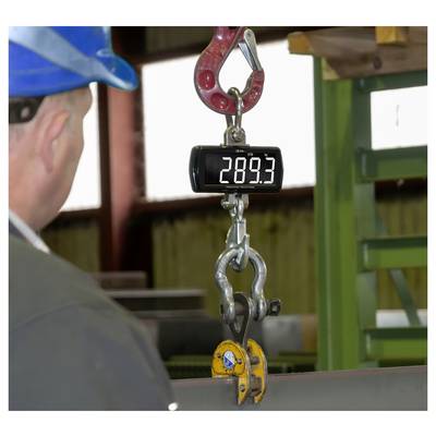Een digitale hangweegschaal toont 289,3 terwijl een werker in een veiligheidhelm een opgehangen metalen haak en klem in een industriële omgeving in de gaten houdt.