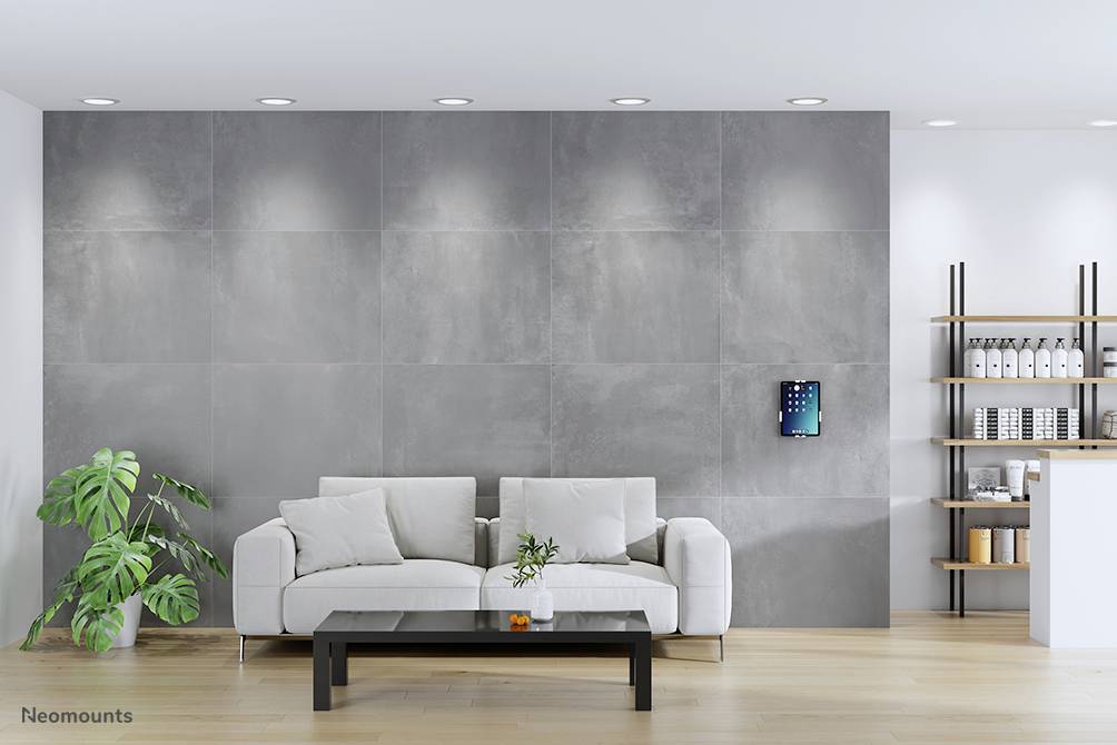 Een modern woonkamer met een grijze muur, een wit bankstel en salontafel. Aan de muur hangt een scherm. Rechts staan boekenkasten.