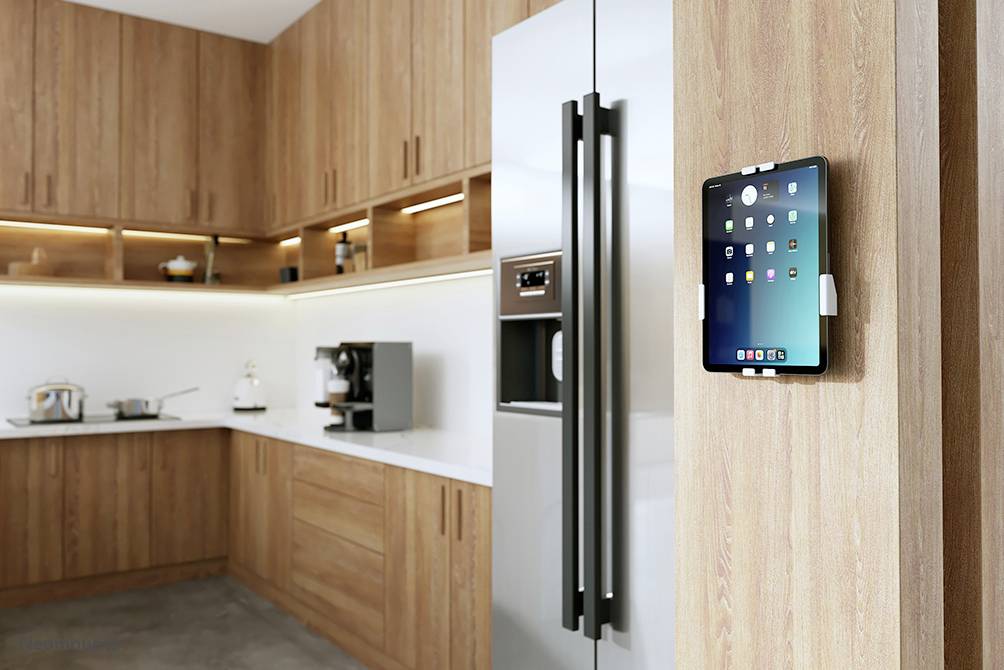 Moderne keuken met houten kasten, grote RVS-koelkast en tablet aan de muur. Heldere verlichting benadrukt minimalistisch design.