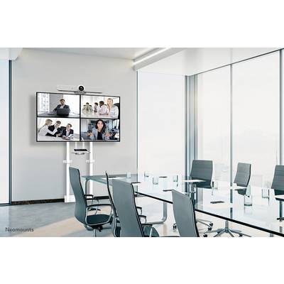 Een vergaderzaal met een glazen tafel en zwarte stoelen. Aan de muur een groot scherm dat een videoconferentie met vier deelnemers weergeeft.