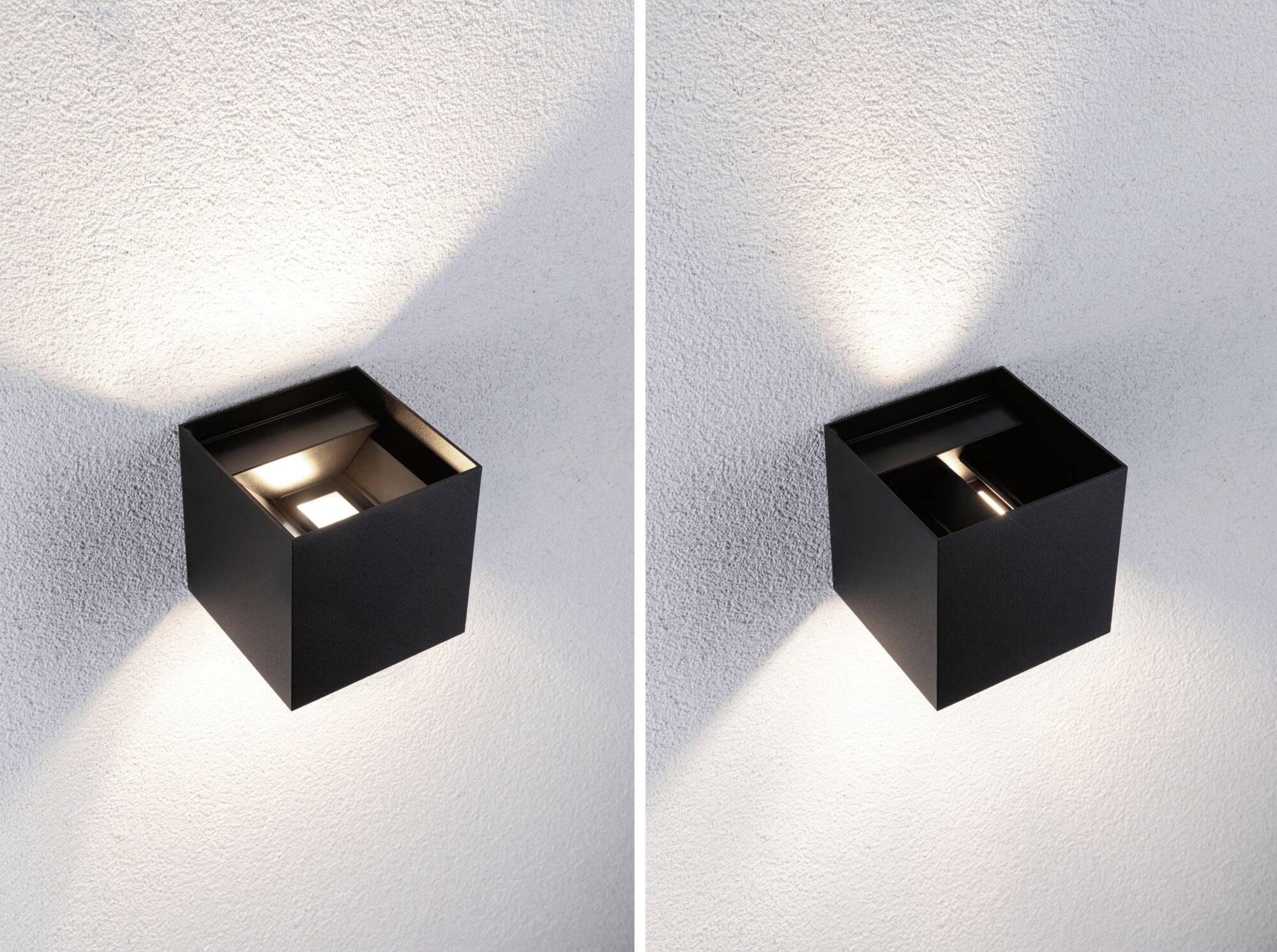 Twee zwarte, kubische buitenlampen aan een muur. De linker lamp schijnt sterker naar boven en beneden, de rechter minder intensief.