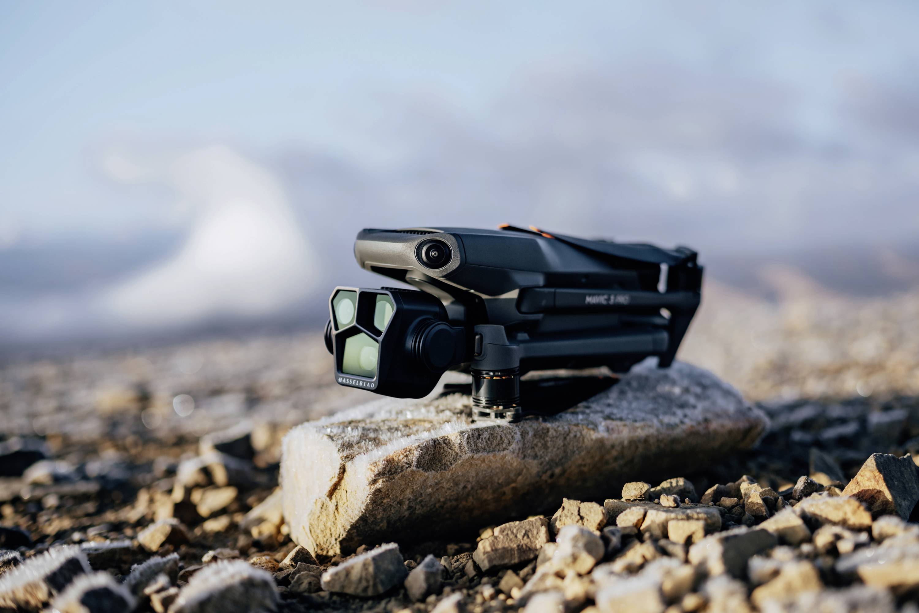 Een opvouwbare drone ligt op een steen in een rotsachtig landschap met een onscherpe lucht op de achtergrond.