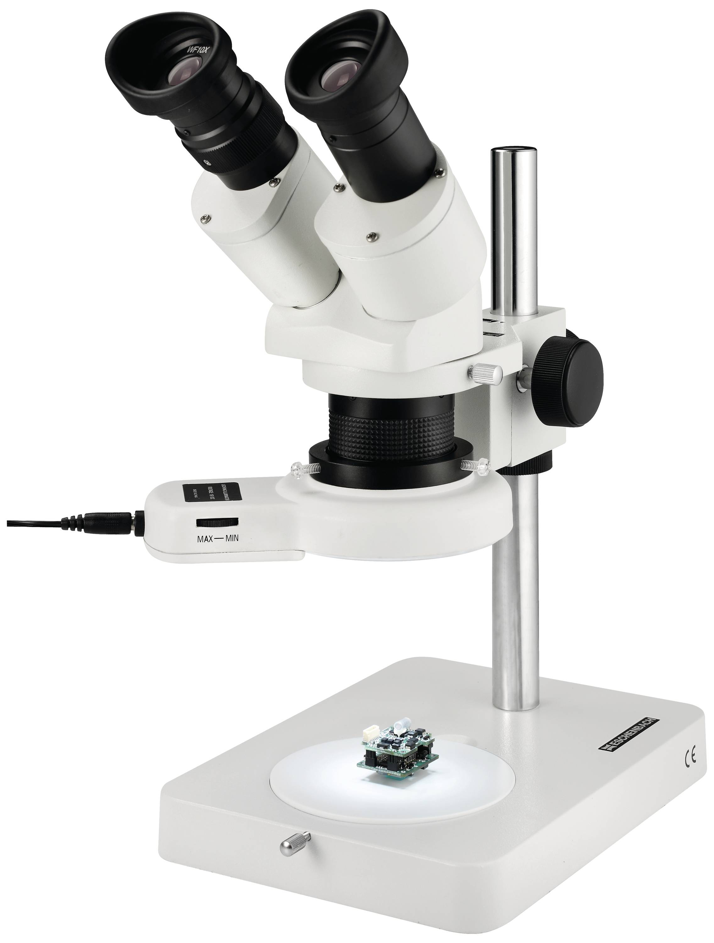 Een wit stereomicroscoop met twee oculairen staat op een tafel. Eronder ligt een kleine elektronische schakeling op de verlichte voet.
