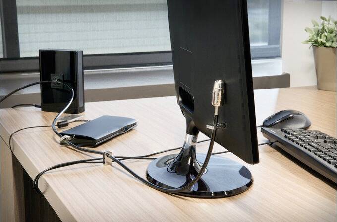 Een bureau met een computerbeeldscherm, een externe harde schijf, een laptop en een toetsenbord, allemaal met elkaar verbonden.
