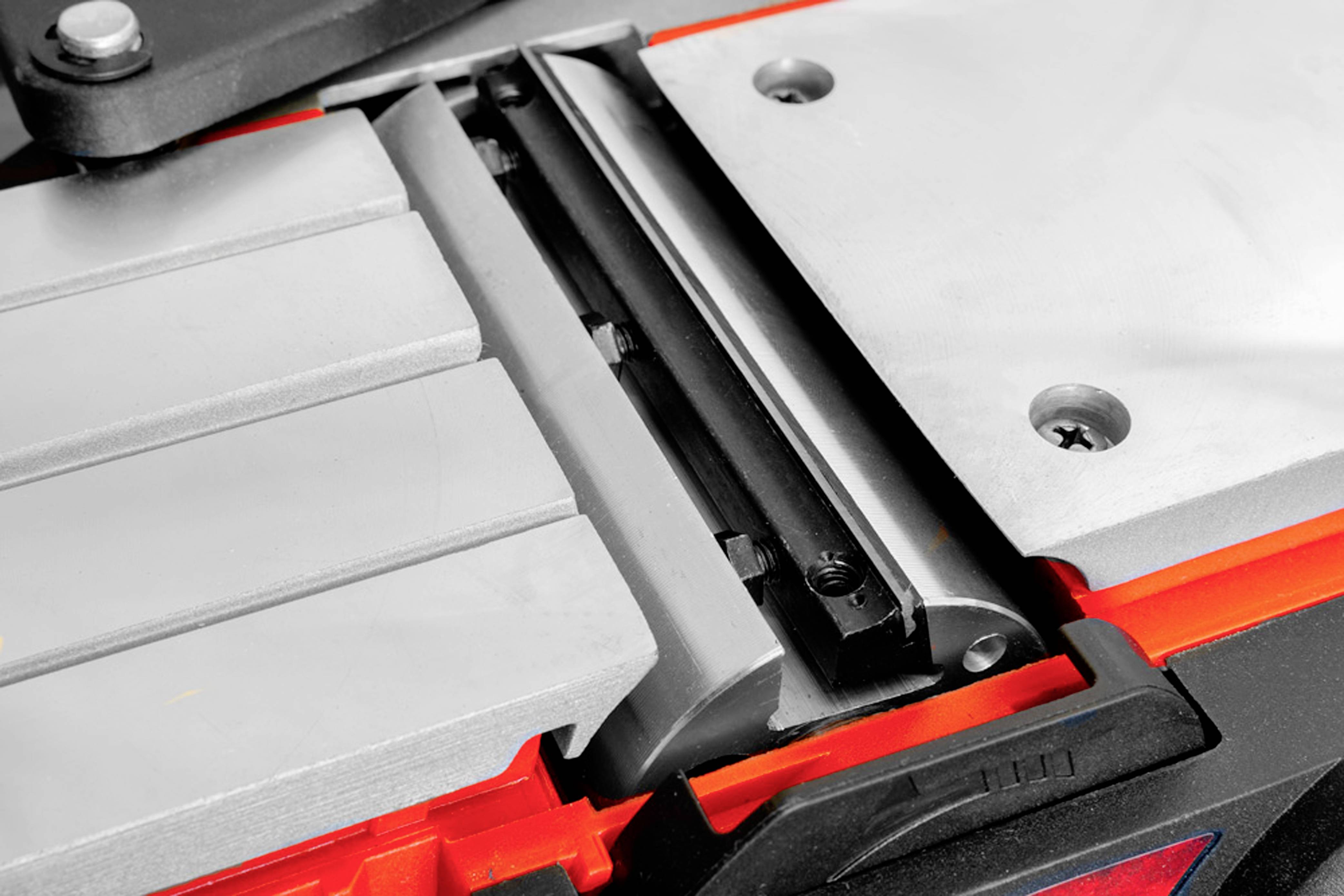 Close-up van een metalen klemmsysteem op een werkbank. De klem is geopend om materiaal vast te houden.