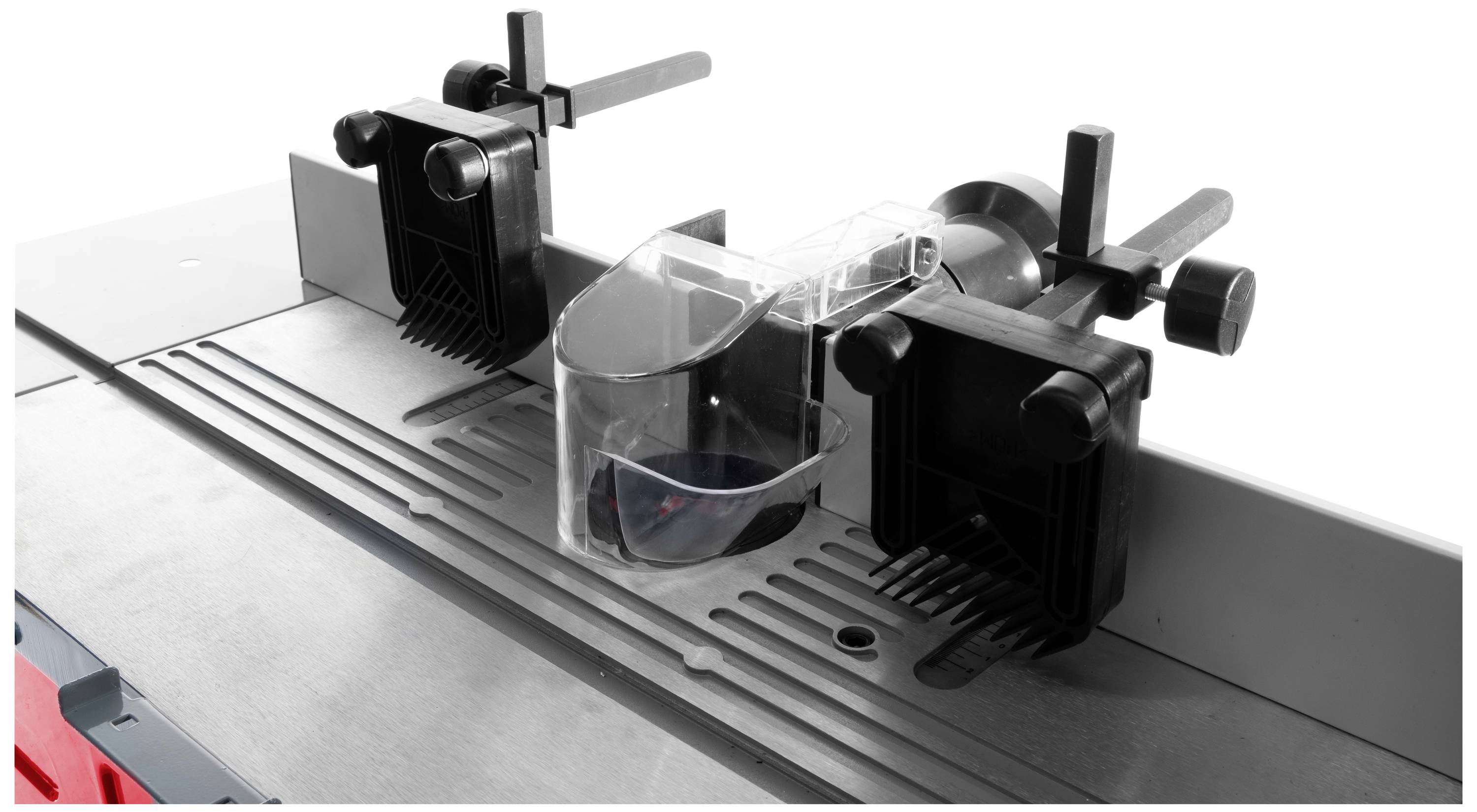 Een freesmachine met twee zwarte klemmen en een doorzichtige beschermkap boven op een metalen tafel.