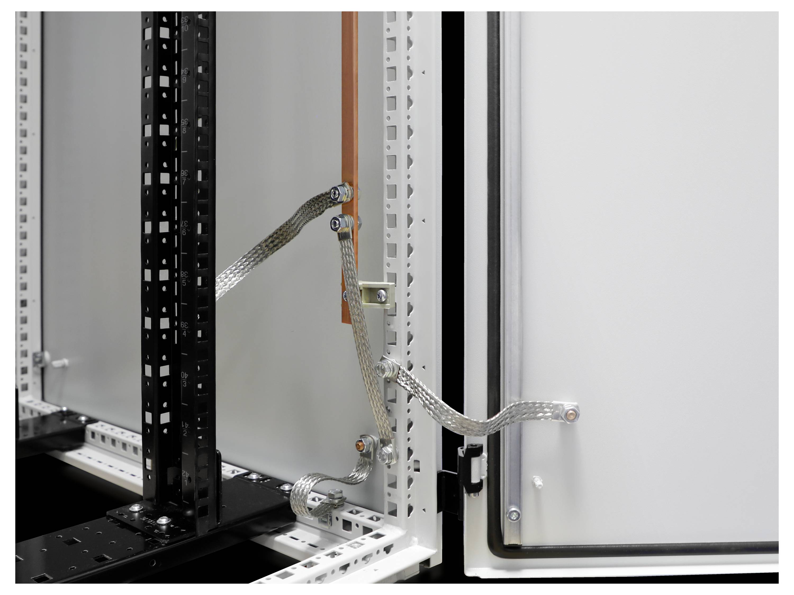 Elektriciteitskast met open deur toont bekabeling en aardingslijnen. Aan de binnenkant zijn metalen frames zichtbaar met bevestigde kabels.