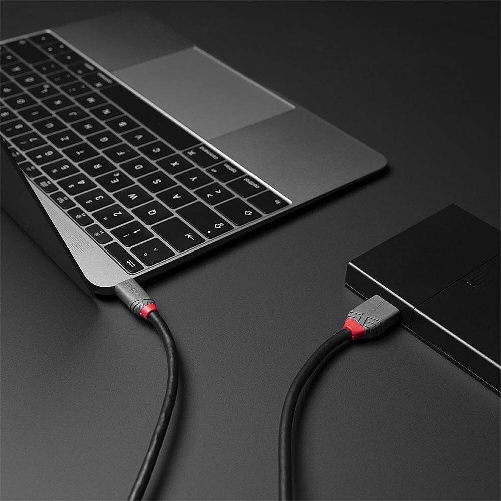 Een laptop is via een kabel aangesloten op een extern apparaat. Het laptopdesign is modern met een donker toetsenbord.