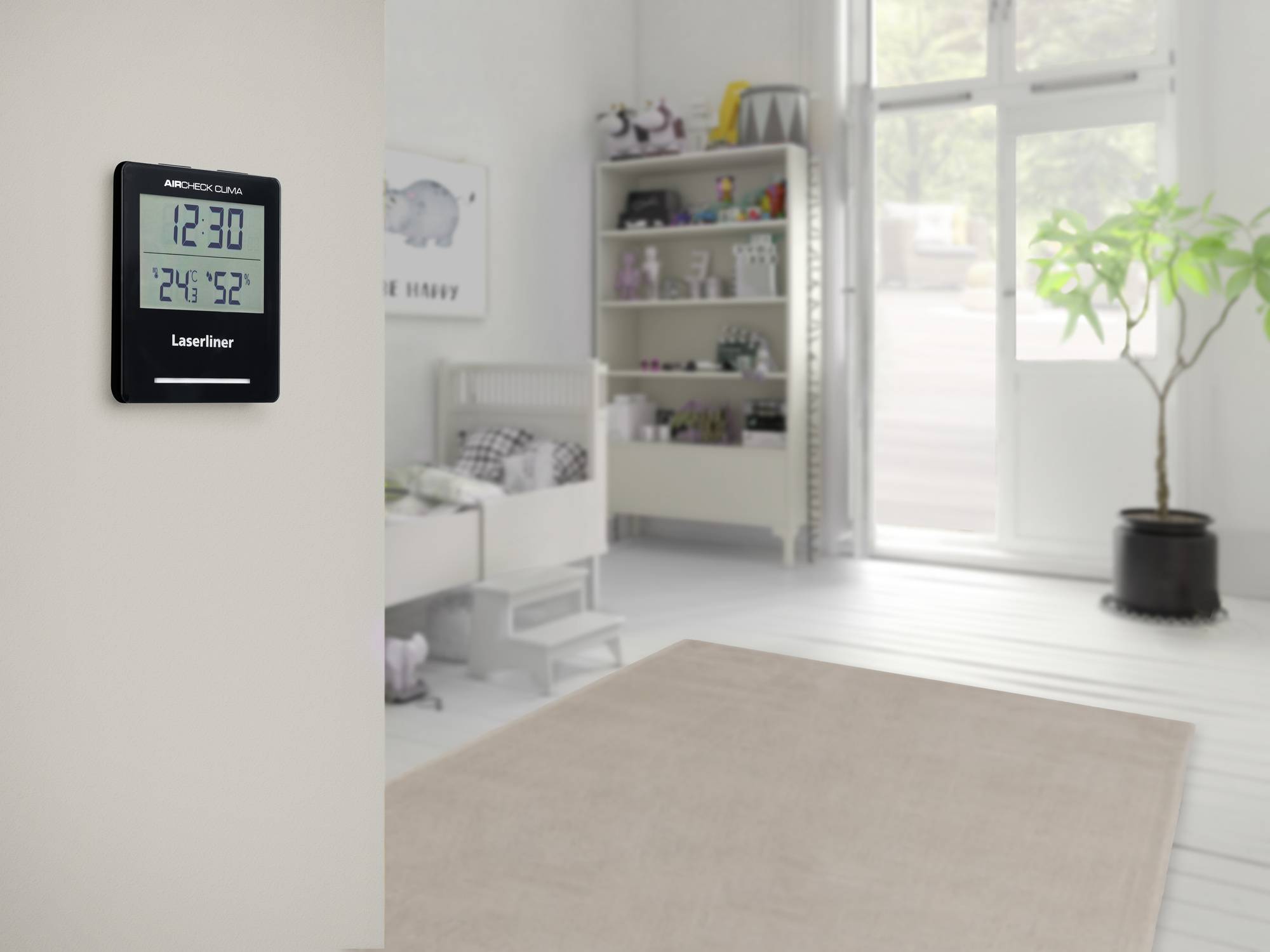 Een kinderkamer met vloerbedekking, een bed en een rek vol speelgoed. Links aan de muur hangt een digitale thermometer.
