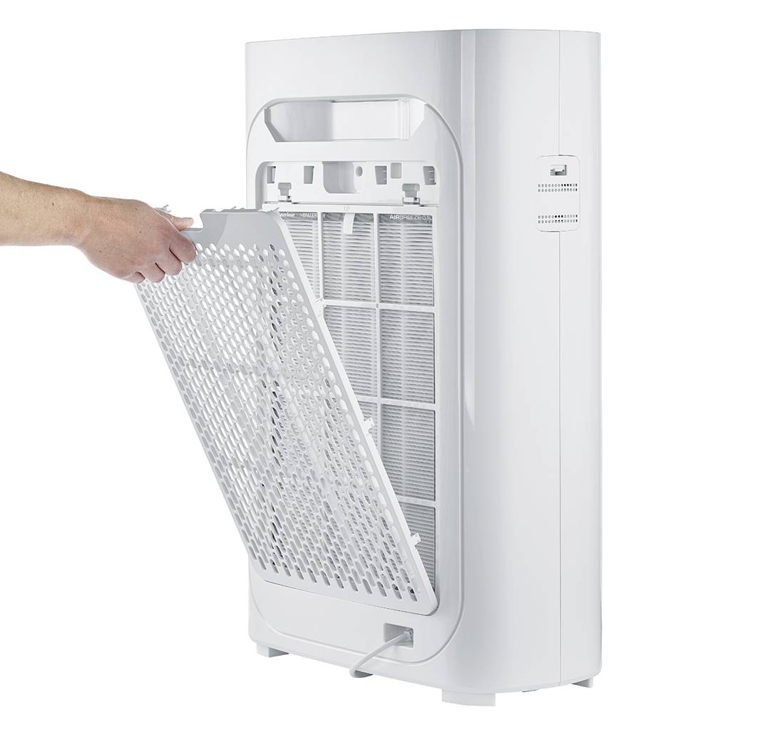 Een persoon verwijdert het filter van een witte luchtreiniger. Het apparaat staat rechtop terwijl het filter wordt verwijderd voor reiniging.