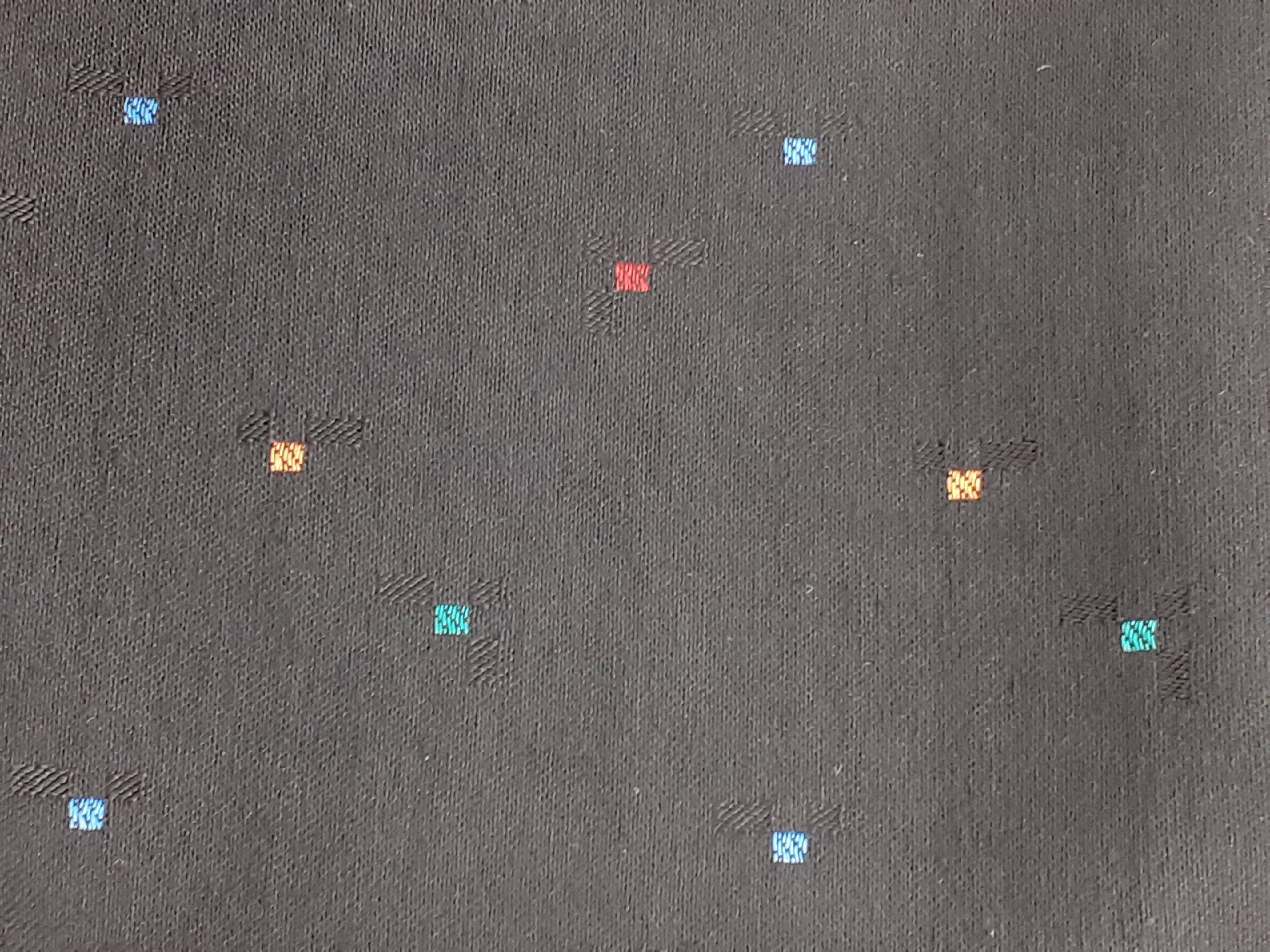 Donkergrijs stof met verspreide kleine vierkantjes in blauw, rood en oranje.