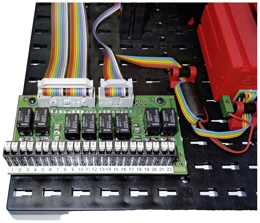 Gekleurde kabels zijn gemonteerd op een elektronische printplaat op een zwart rooster. Rechterplaat verbonden met een rood behuizing.