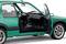 Groene auto met open bestuurdersdeur, onthult het zwarte interieur en dashboard. Het voertuig staat stil en is rijklaar.