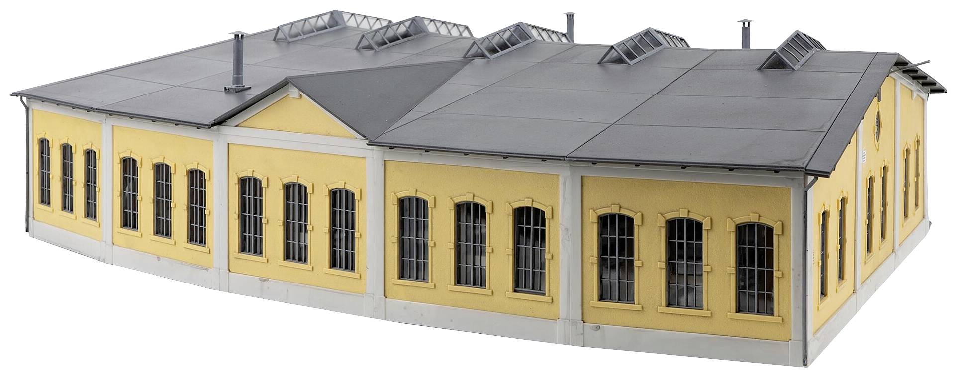 Geel gebouw met zwarte daken en ramen, gezien in perspectief. Het lijkt een historisch industrieel gebouw te zijn.