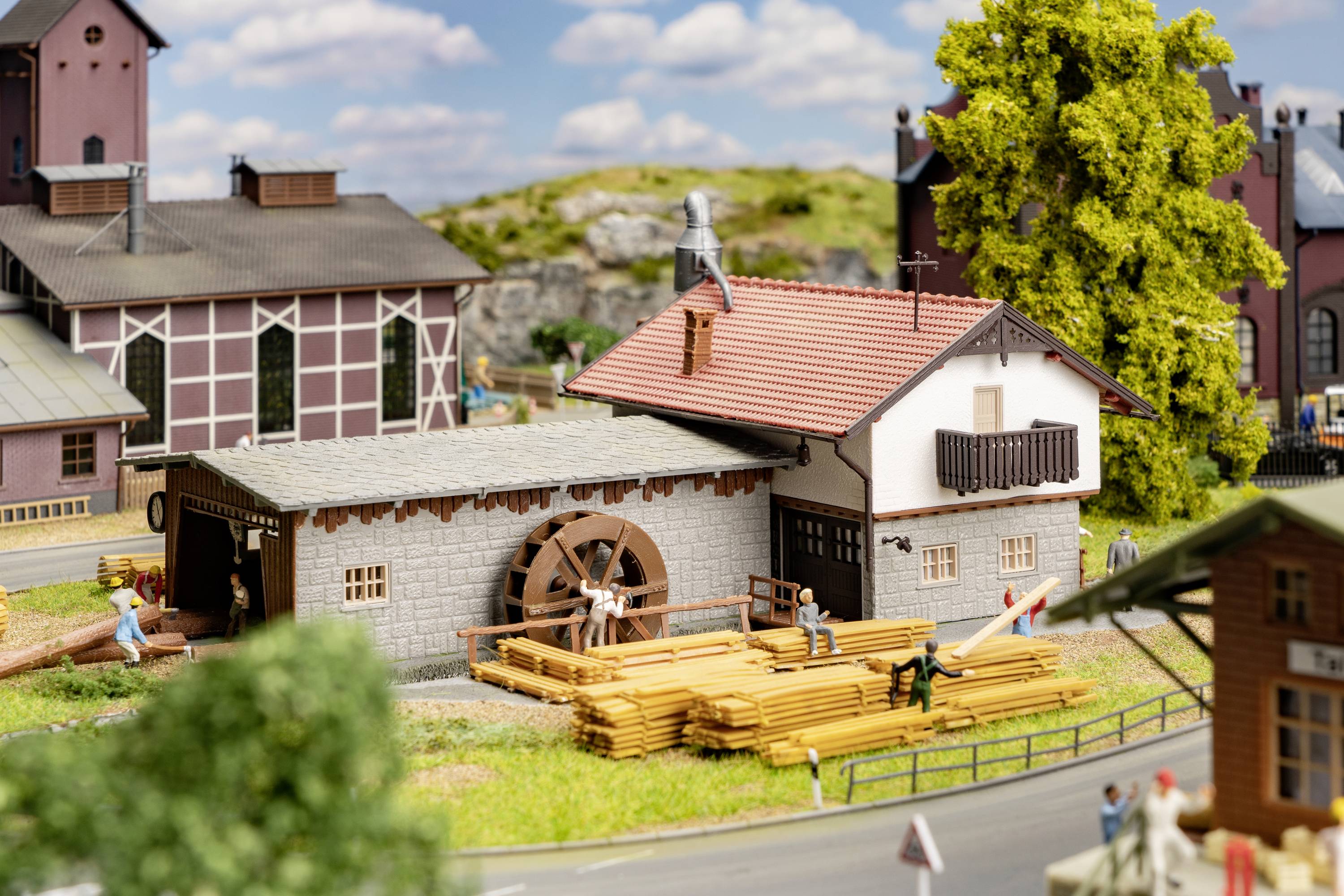 Een miniatuurspoorlandschap met een houtverwerkingsworkshop, omgeven door figuren en bomen, toont alledaagse werkactiviteiten.