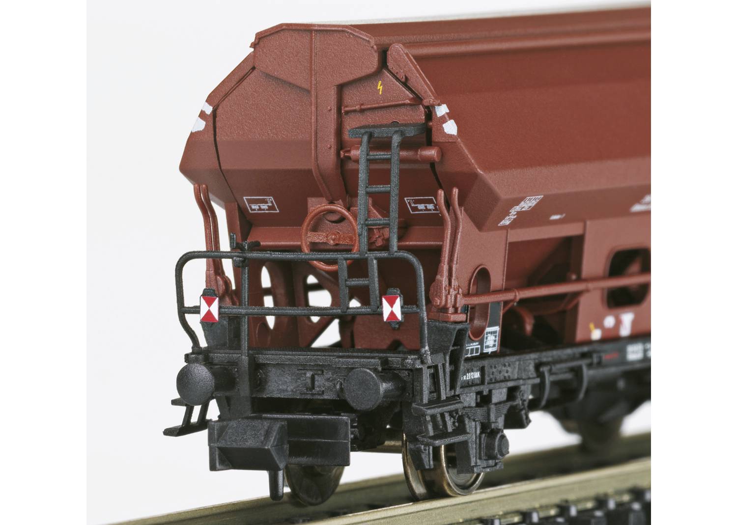 Een bruine goederenwagon met ladder en veiligheidssignalering op een spoor. Gedetailleerd model van een treinwagon voor modelspoorbanen.