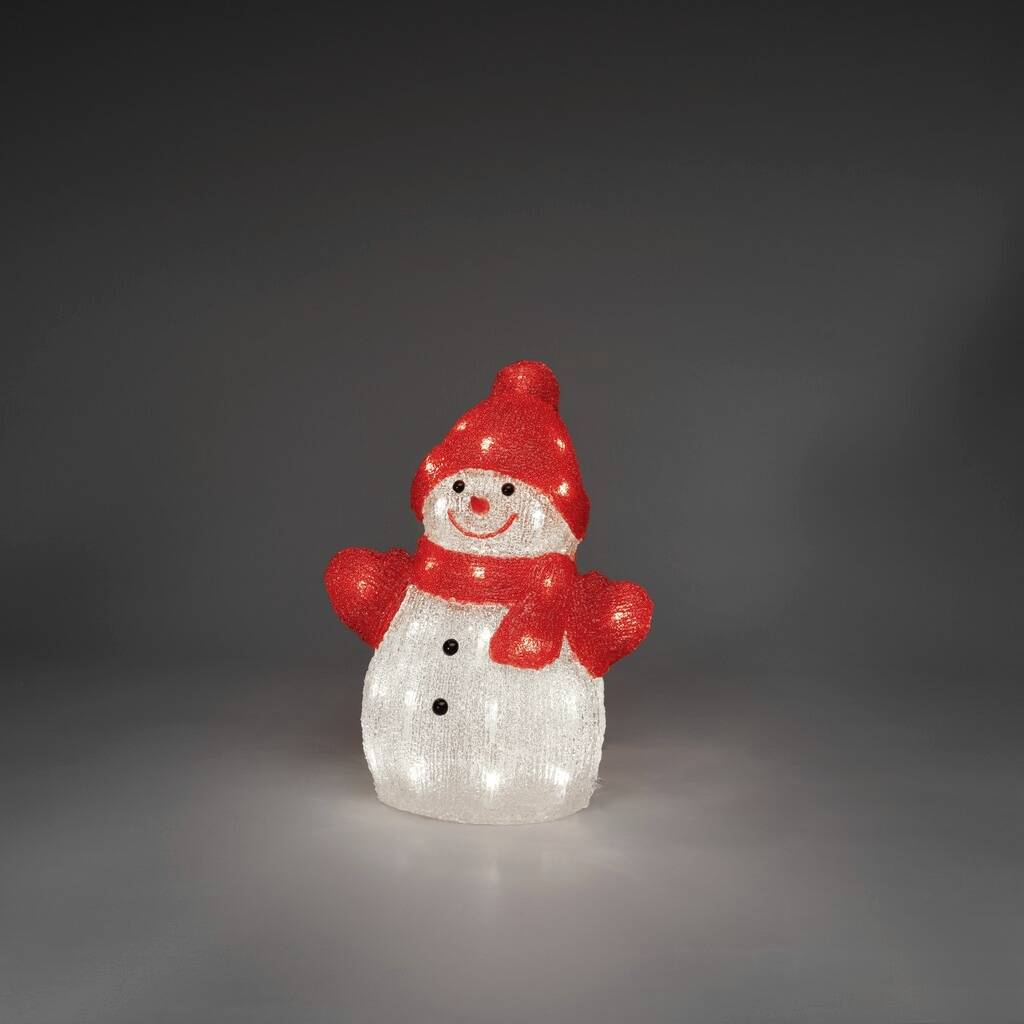 Een verlichte sneeuwpop met een rode hoed en sjaal straalt in een donkere ruimte. De sneeuwpop glimlacht vriendelijk.