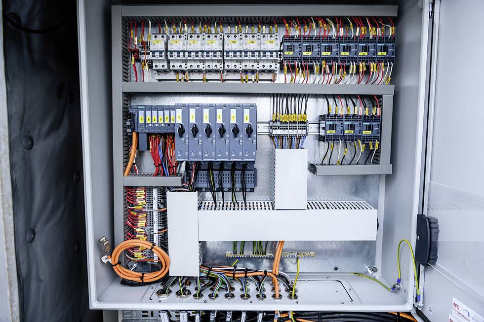 Een geopende elektrische kast vol kleurrijke kabels en schakelaars, toont de complexe bedrading en elektrische aansluitingen aan de binnenkant.