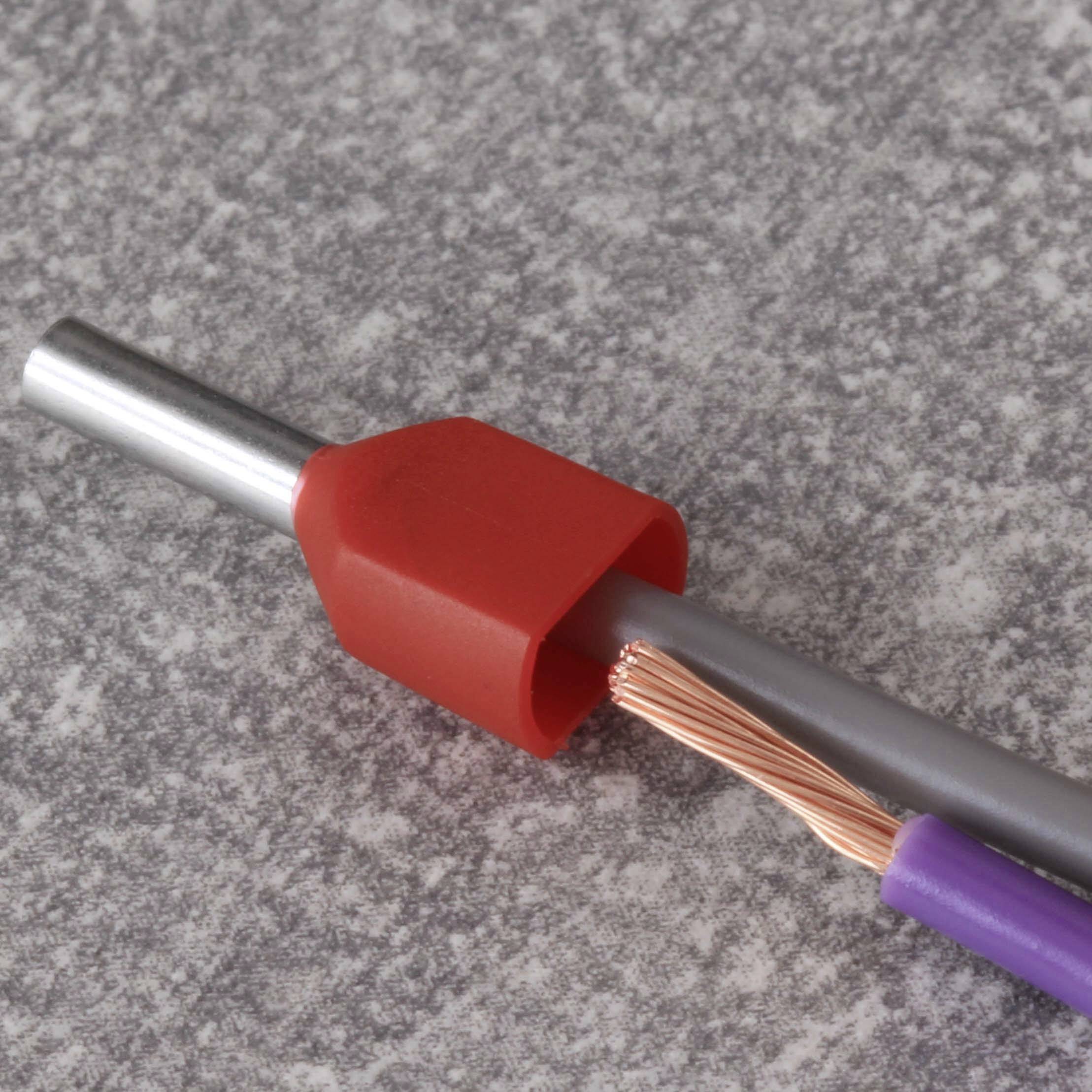 Een grijs kabel met ontblote koperdraad wordt gestoken in een rode adereindhuls, tegen een grijze achtergrond.
