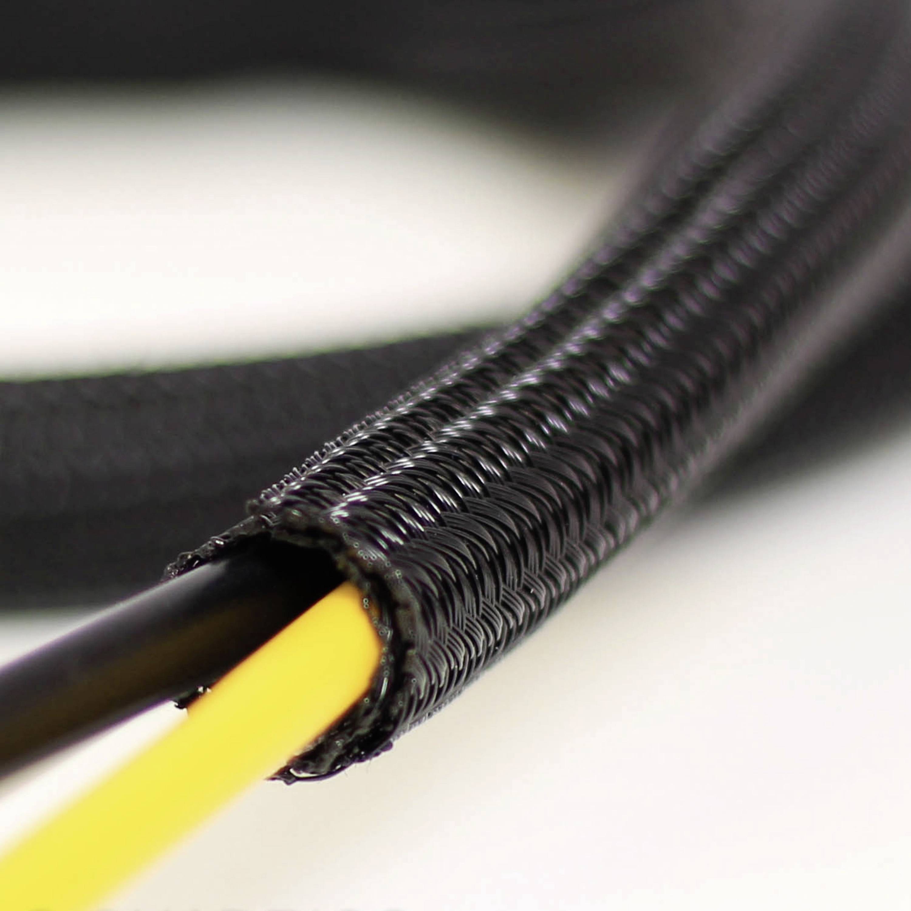 Close-up van een zwarte, gevlochten kabelgootslang met een geel kabel erbinnen. De slang biedt bescherming en flexibiliteit.