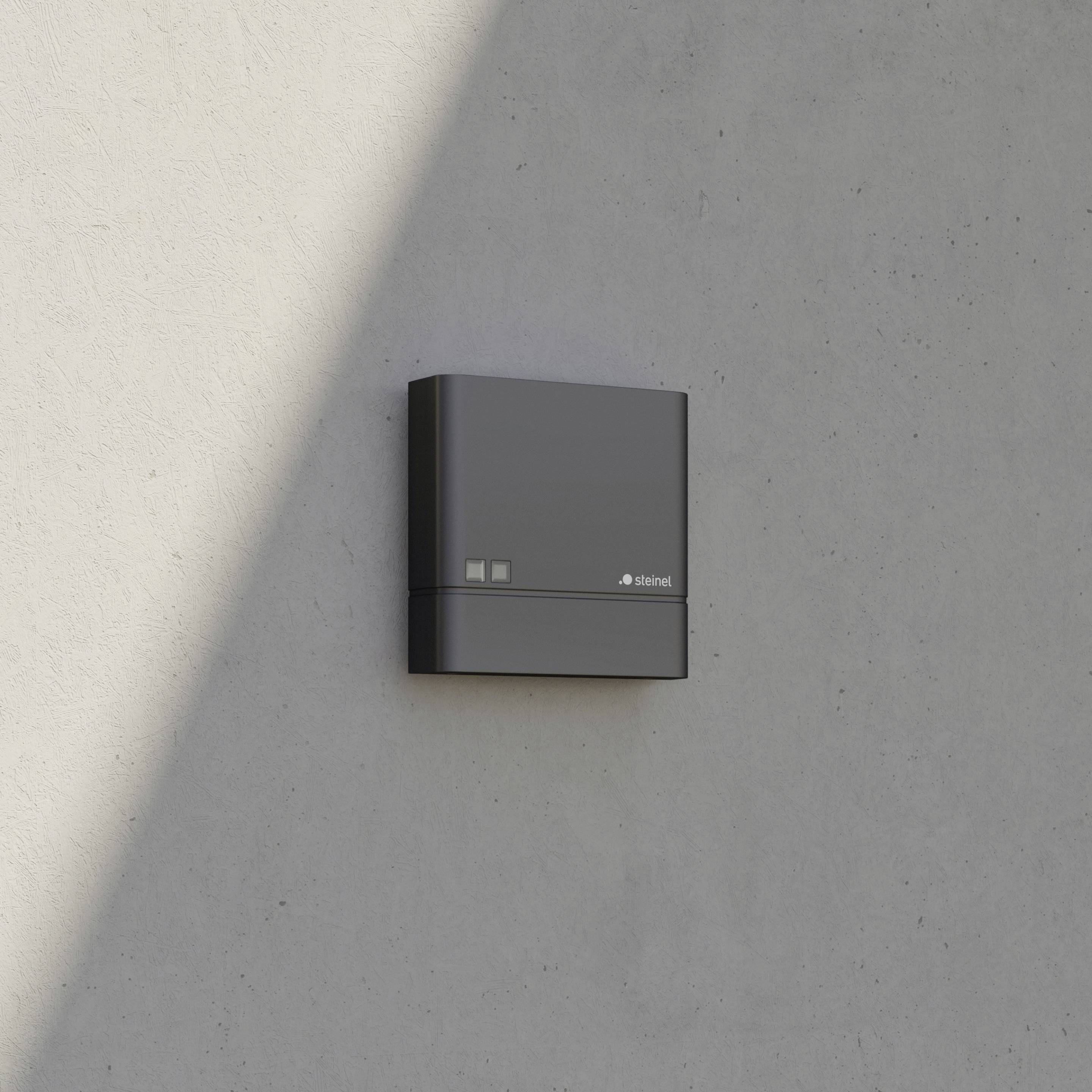 Elektrische installatie gemonteerd aan een betonnen muur, rechthoekige vorm, donkergrijs, met zichtbare merknaam.