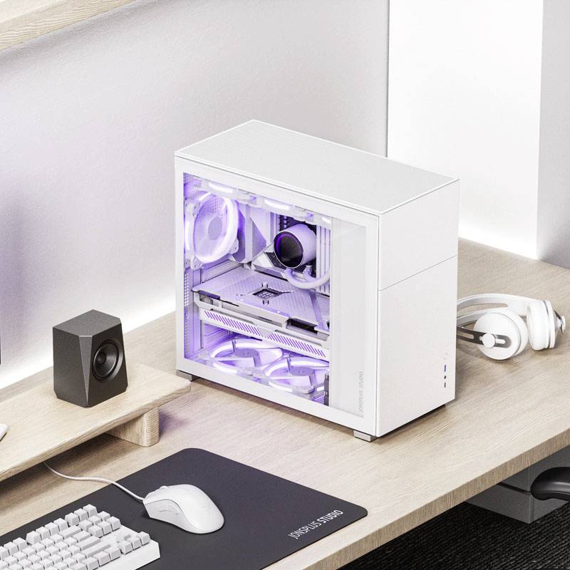 Witte desktopcomputer op een bureau, zijdelings verlicht met paars licht. Ernaast speakers, muismat en koptelefoon.