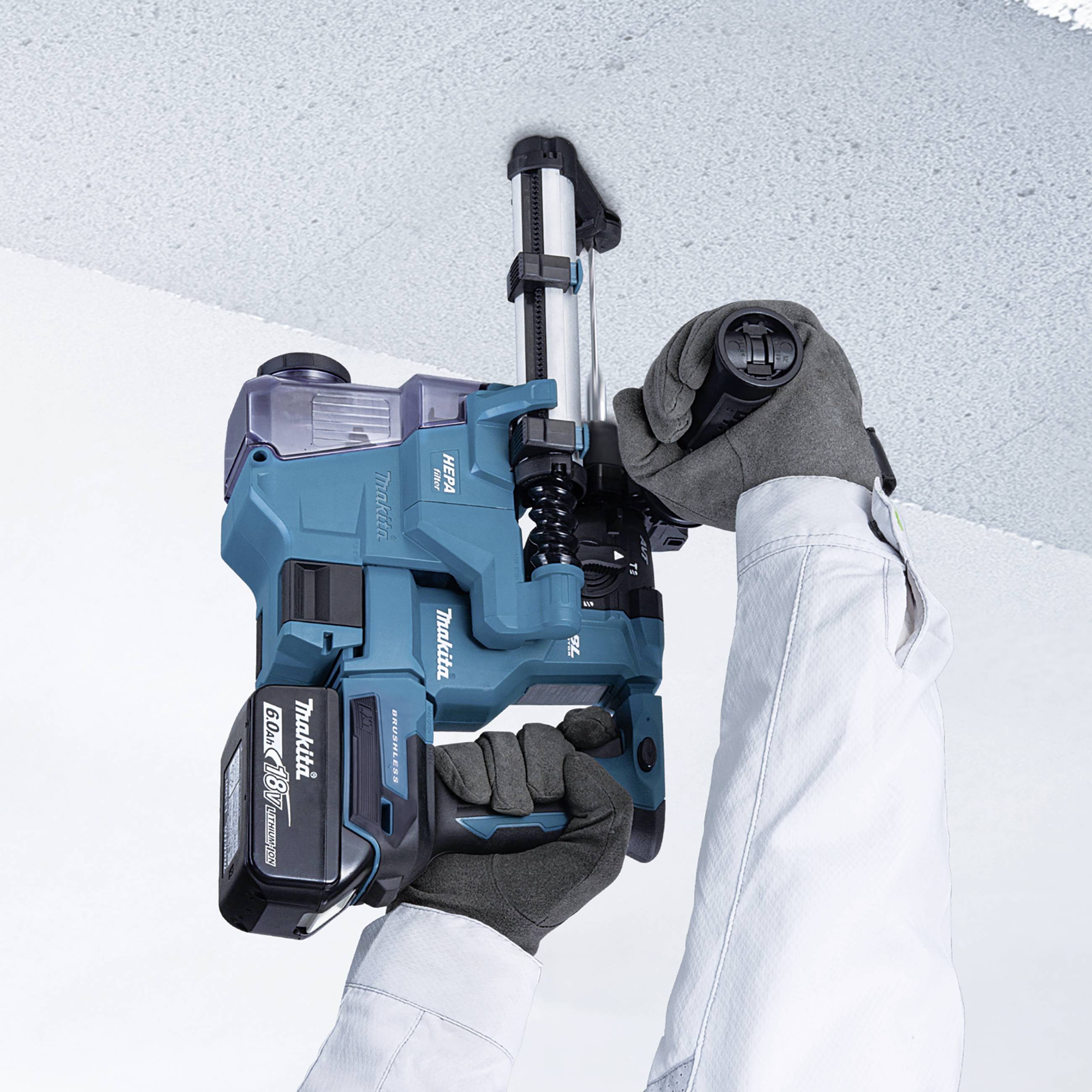 Een persoon draagt handschoenen en houdt een blauw, elektrisch handapparaat dat tegen een muur is gepositioneerd.