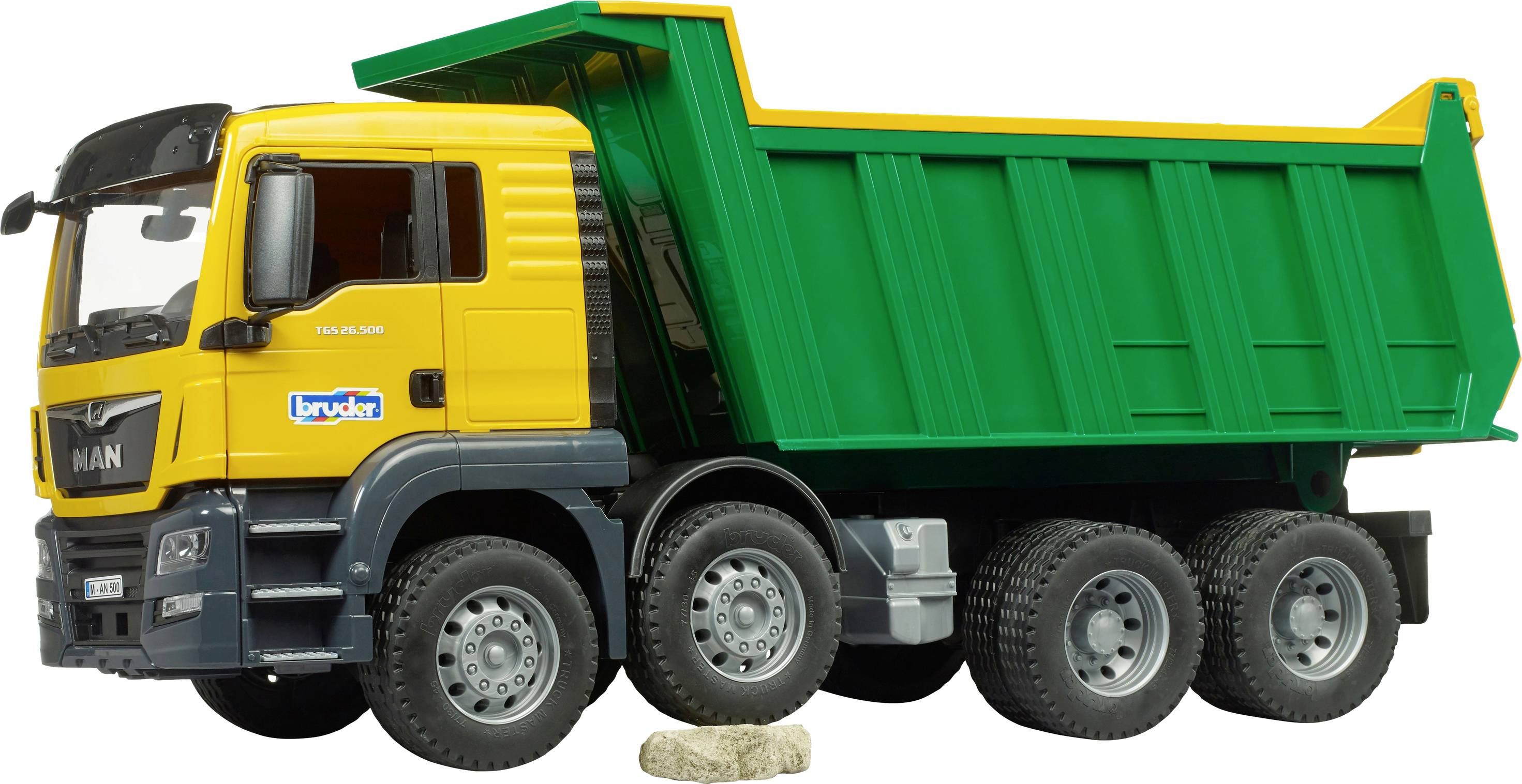 Een gele kiepvrachtwagen met een groene container op een stenige ondergrond. De vrachtwagen heeft zes wielen en wordt getoond vanuit een zijaanzicht.